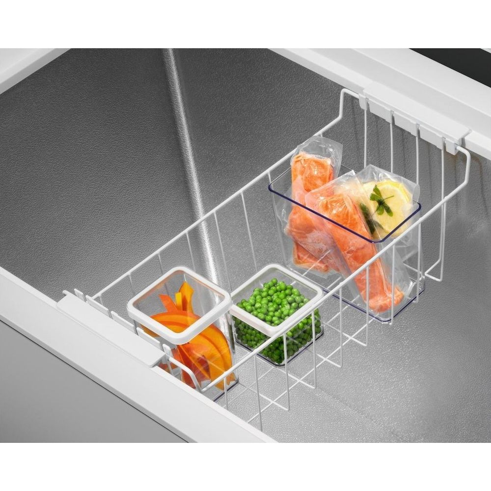Panier de congélateur avec aliments congelés : poisson, petits pois et carottes.