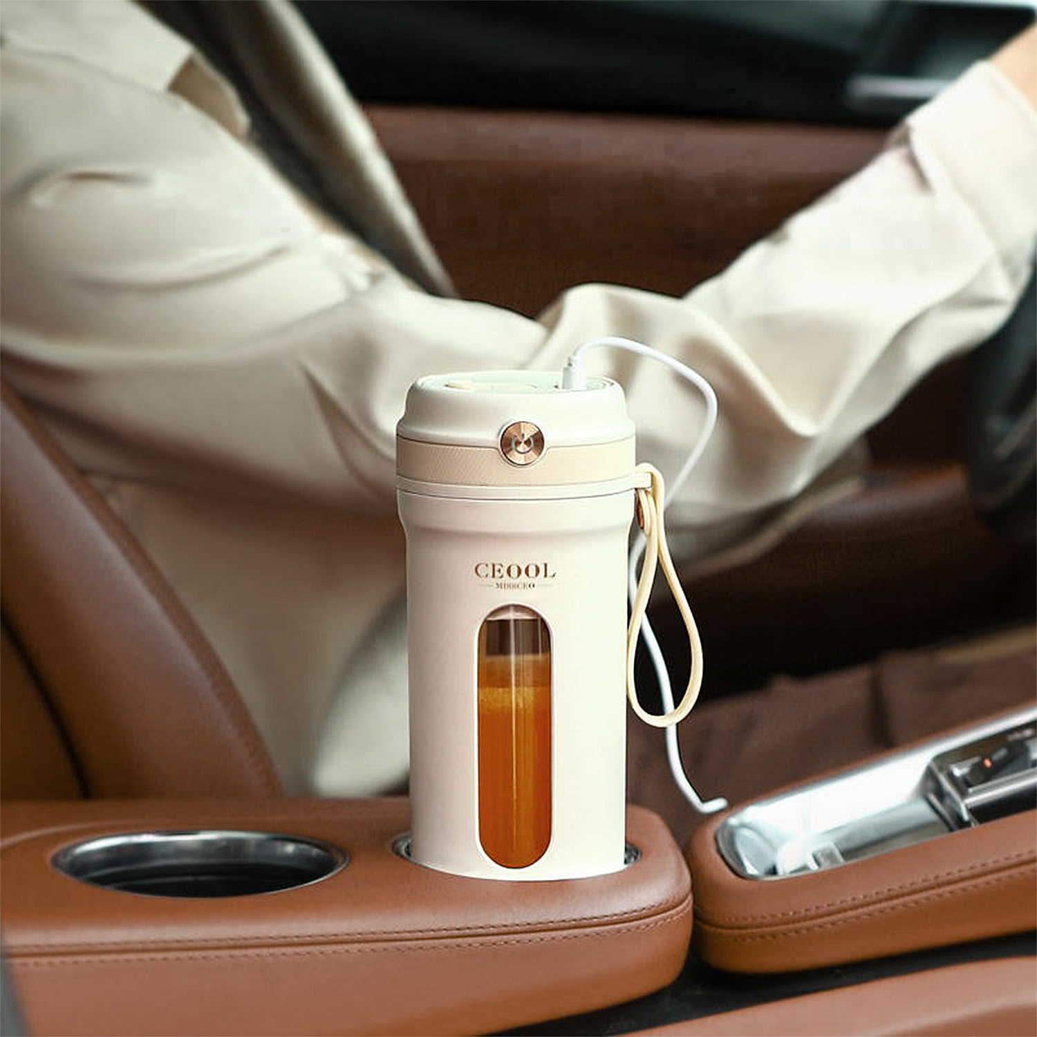 Una licuadora portátil blanca con jugo de naranja está en el portavasos de un auto.