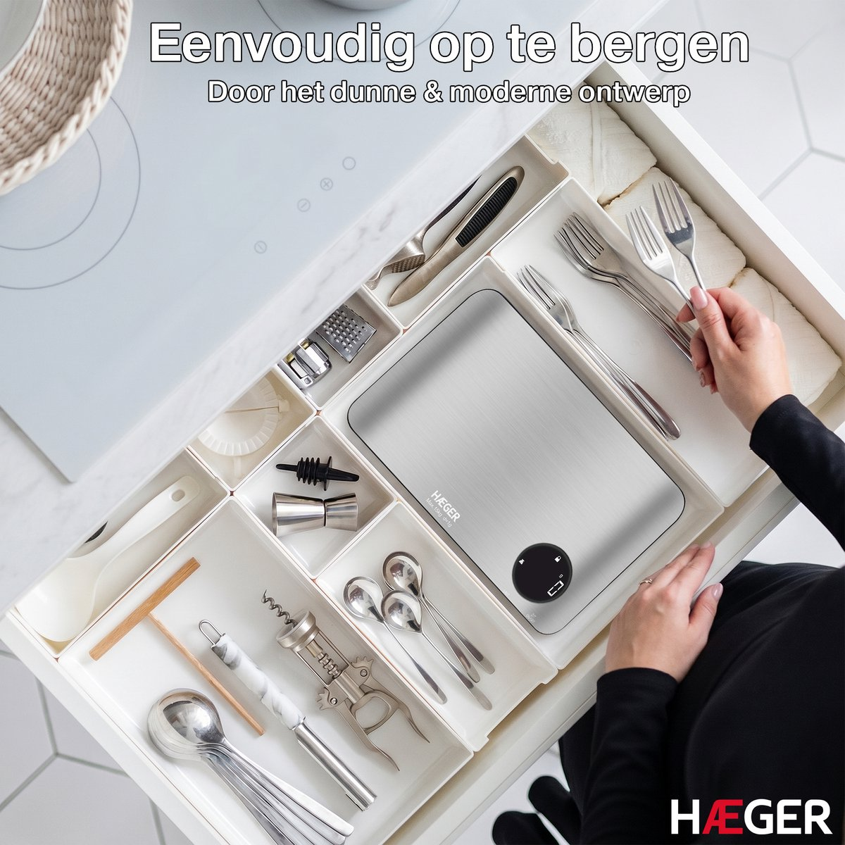 A kitchen drawer with utensils, a scale, and cutlery. Hands sorting forks.