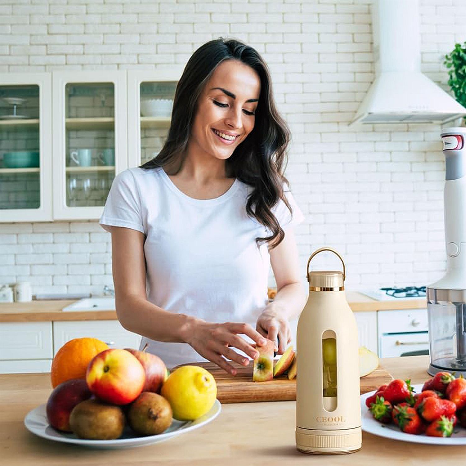 Mujer corta manzana en cocina junto a frutas y licuadora. Cocina luminosa.