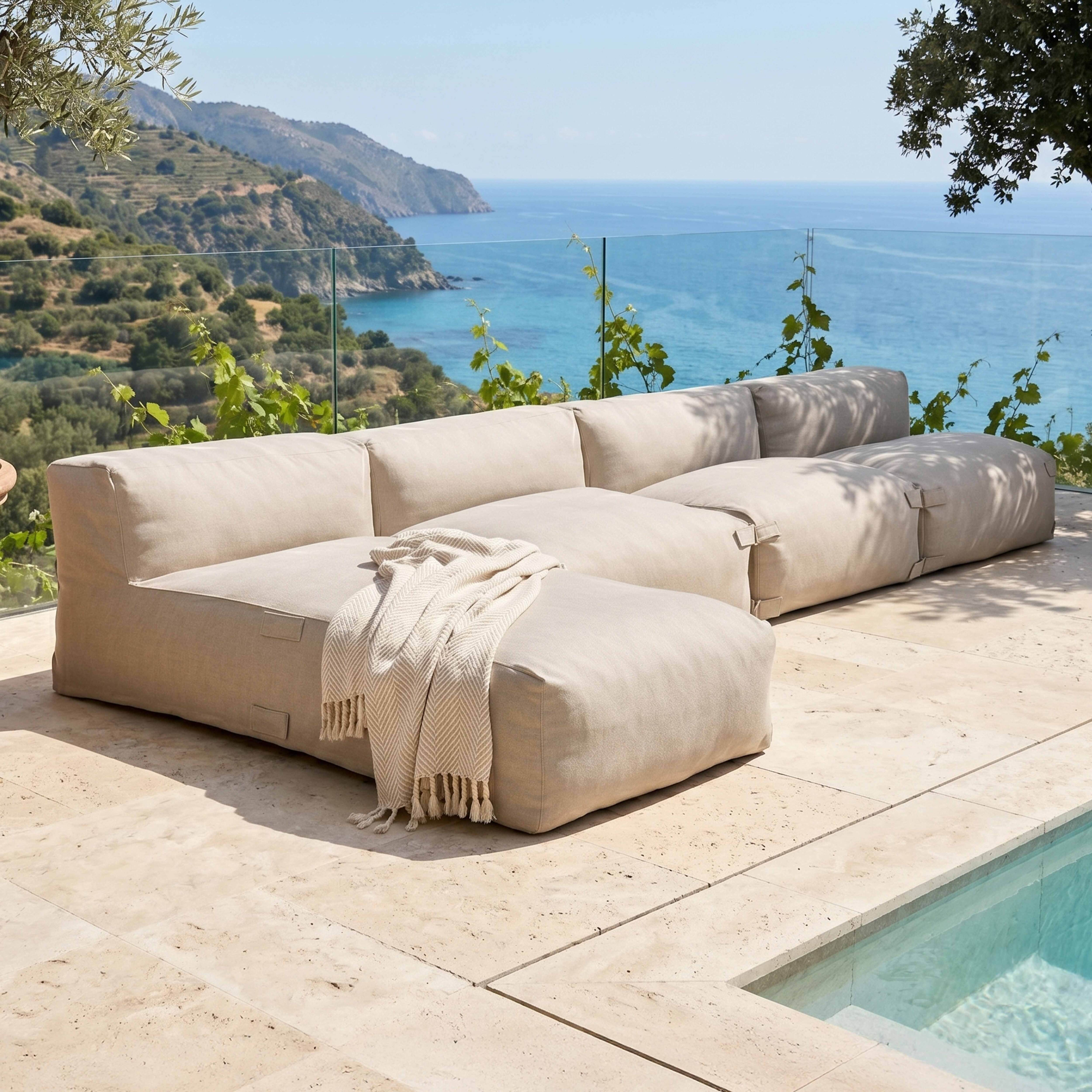 Beige Lounge-Möbel am Pool mit Blick auf das Meer und die Berge.