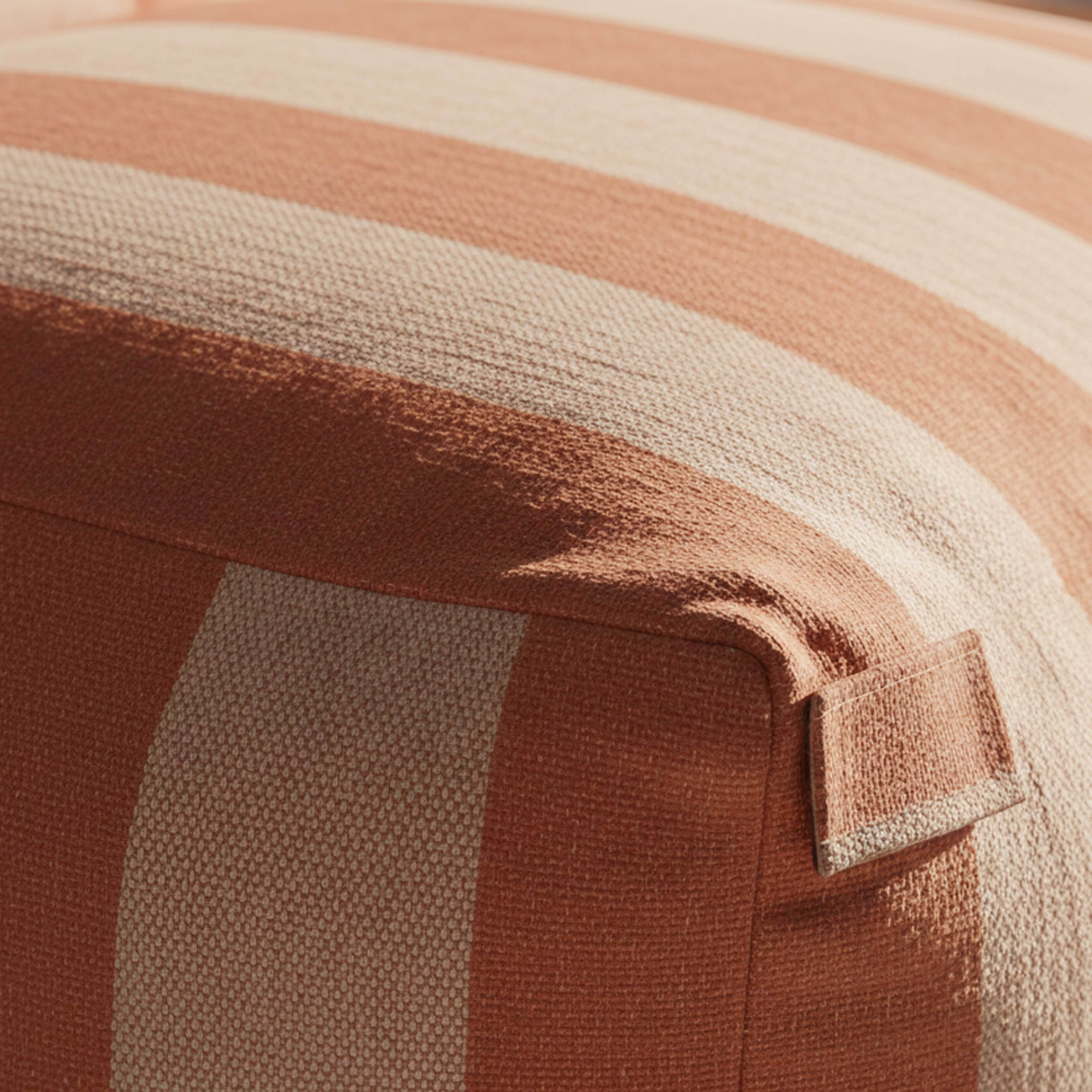 Nahaufnahme eines gestreiften Stoffes in Orange und Beige mit einer sichtbaren Naht.
