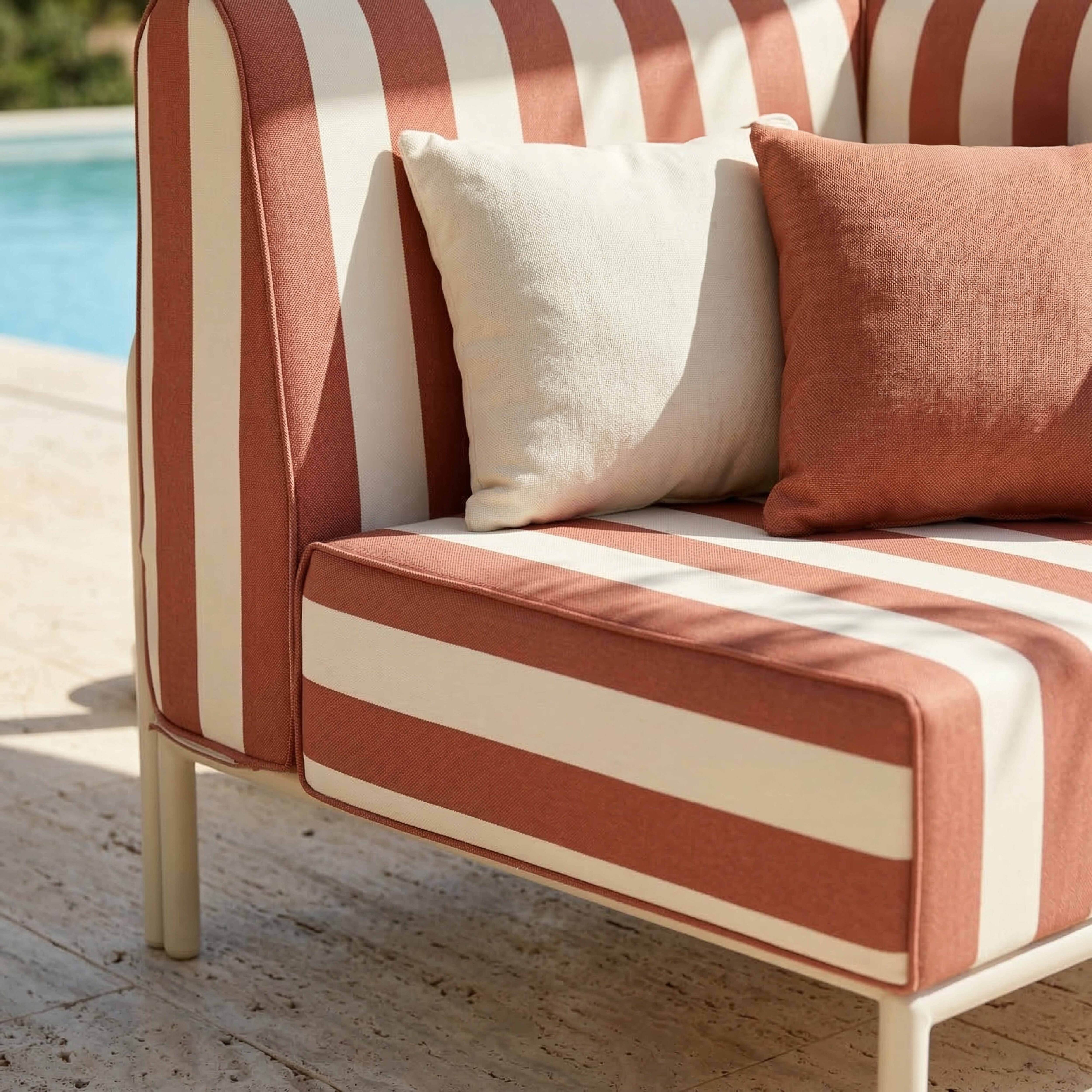 Gestreifte Couch mit zwei Kissen neben einem Pool.