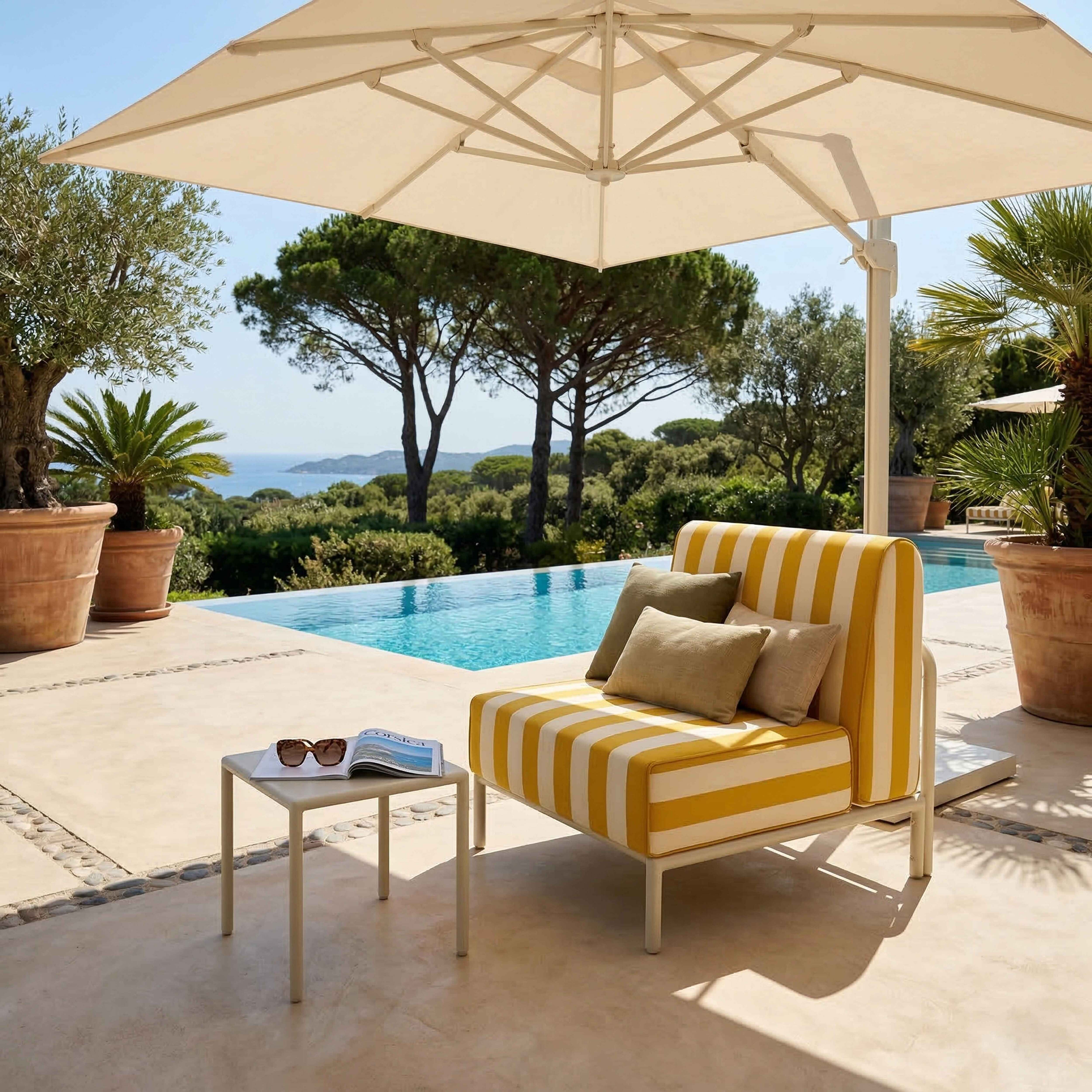 Ein gestreifter Loungesessel neben einem Pool mit Meerblick und Sonnenschirm.