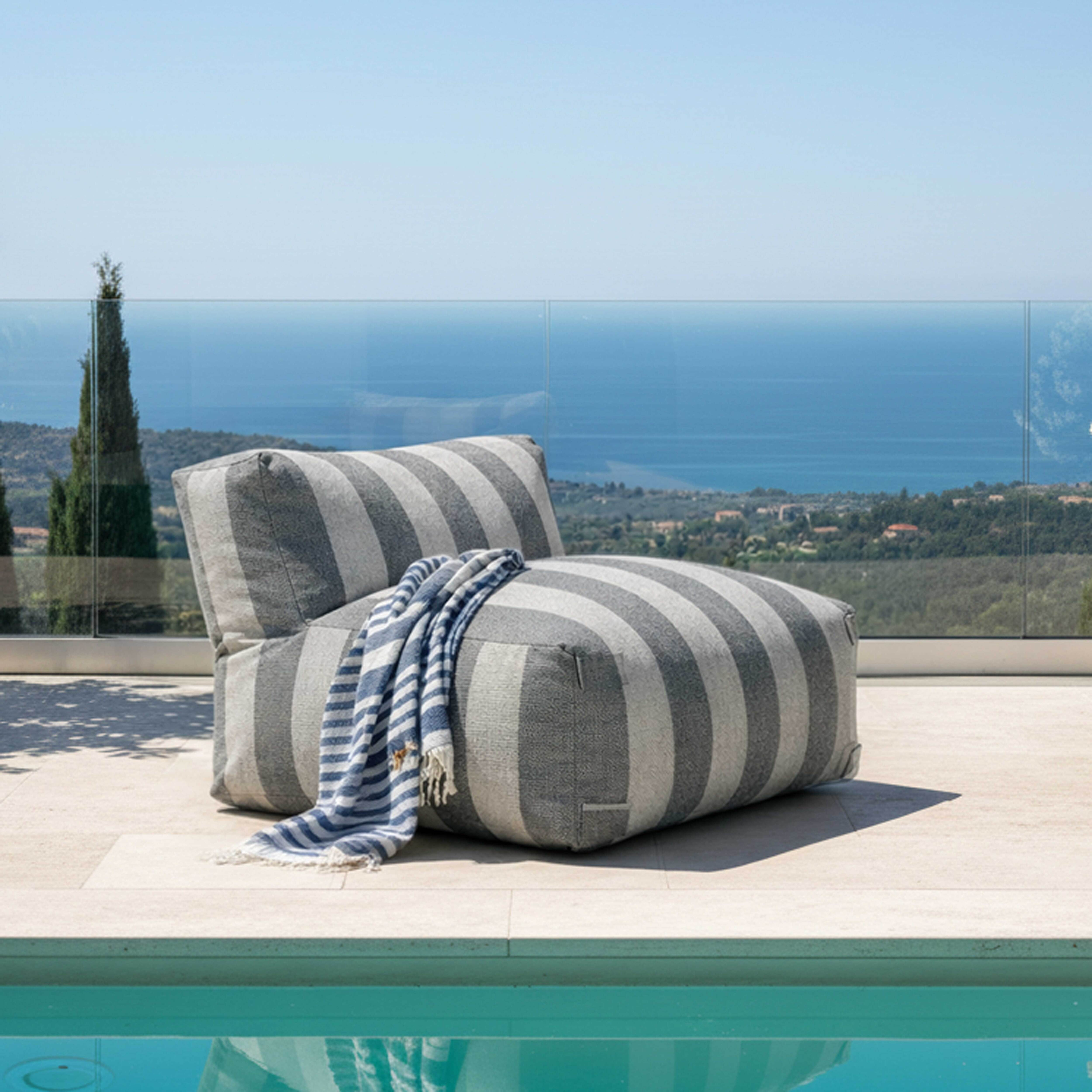 Gestreifter Loungesessel am Pool mit Blick auf das Meer.