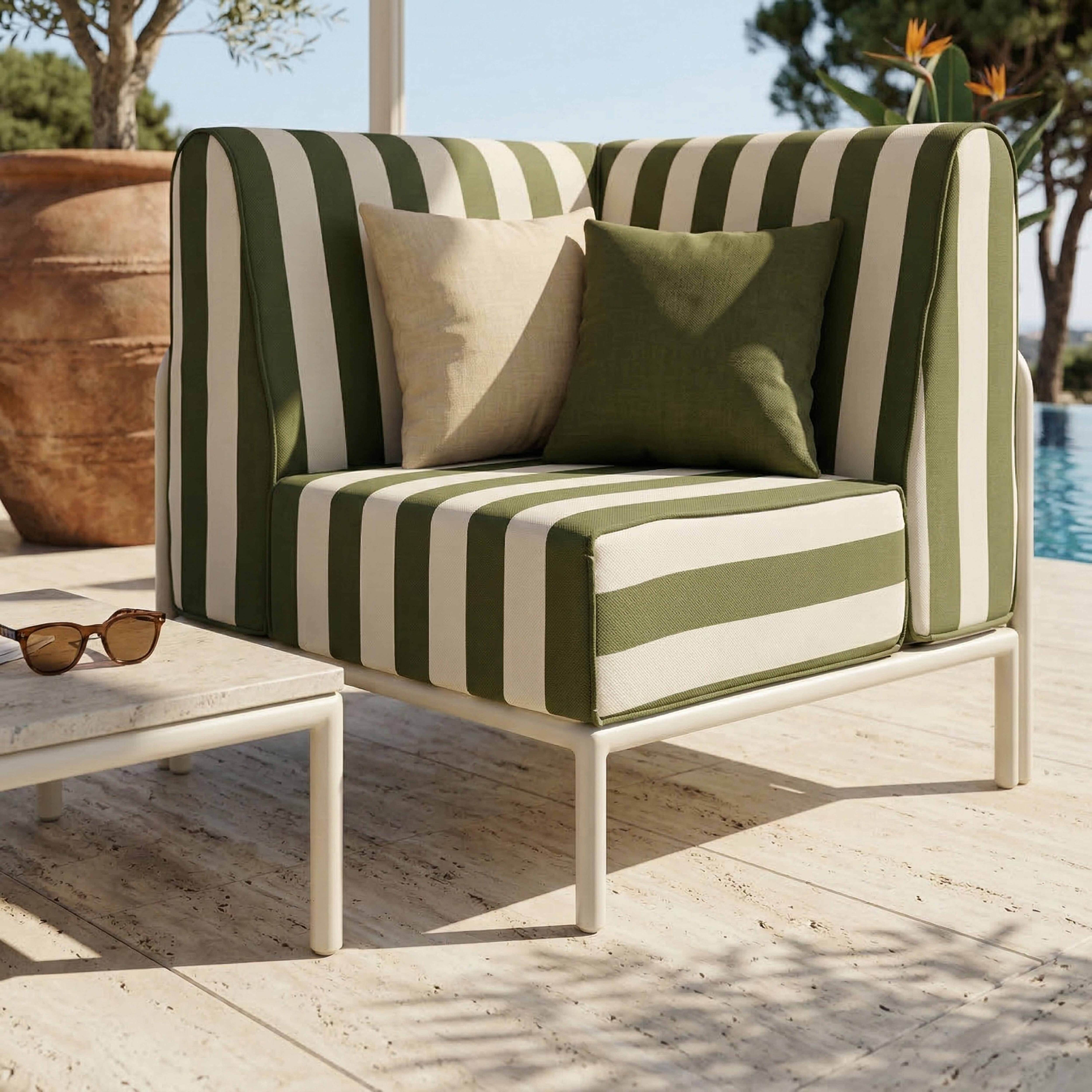 Gestreifter Outdoor-Sessel mit zwei Kissen neben einem Beistelltisch mit Sonnenbrille.