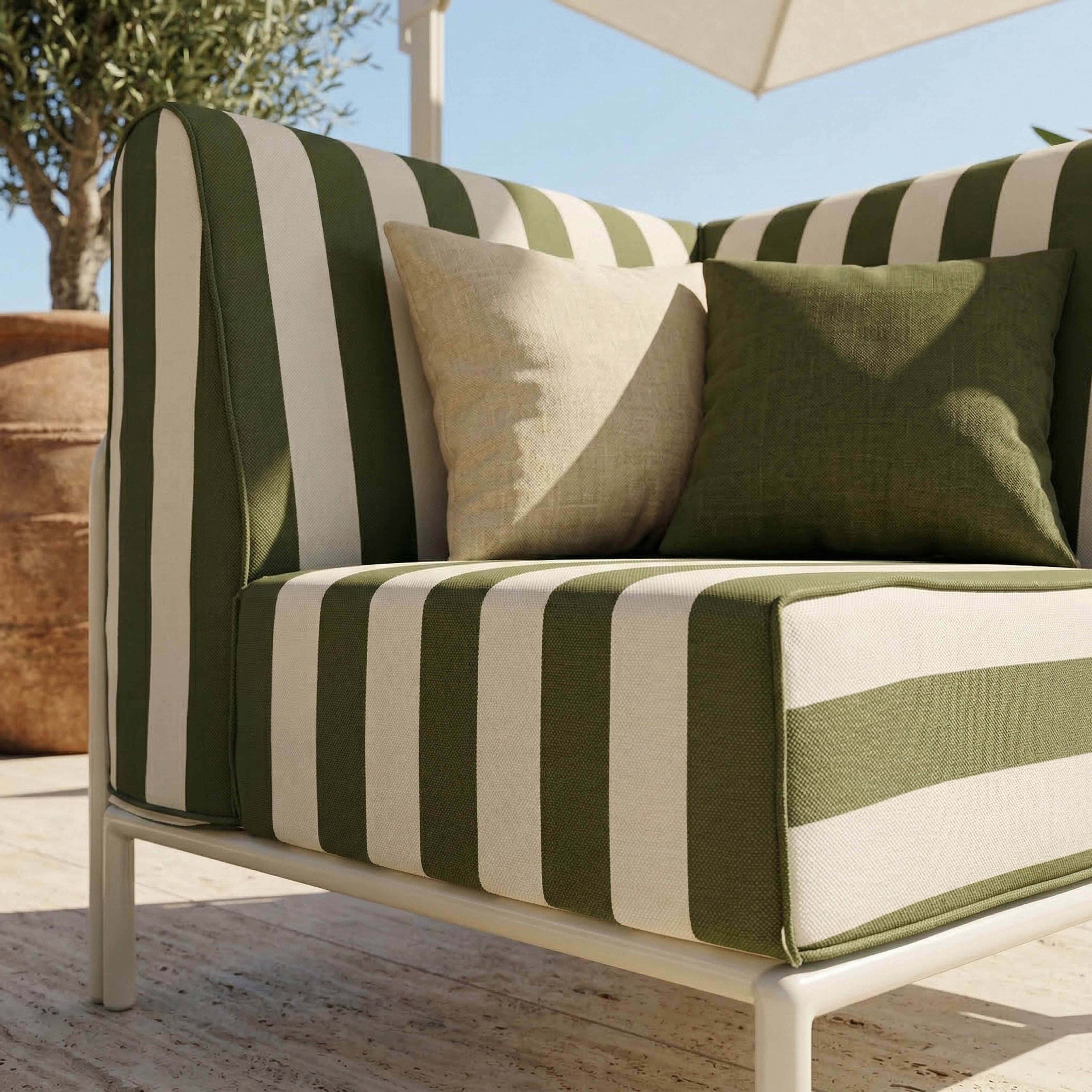 Ein gestreiftes Outdoor-Sofa mit grünen und weißen Streifen, zwei Kissen.