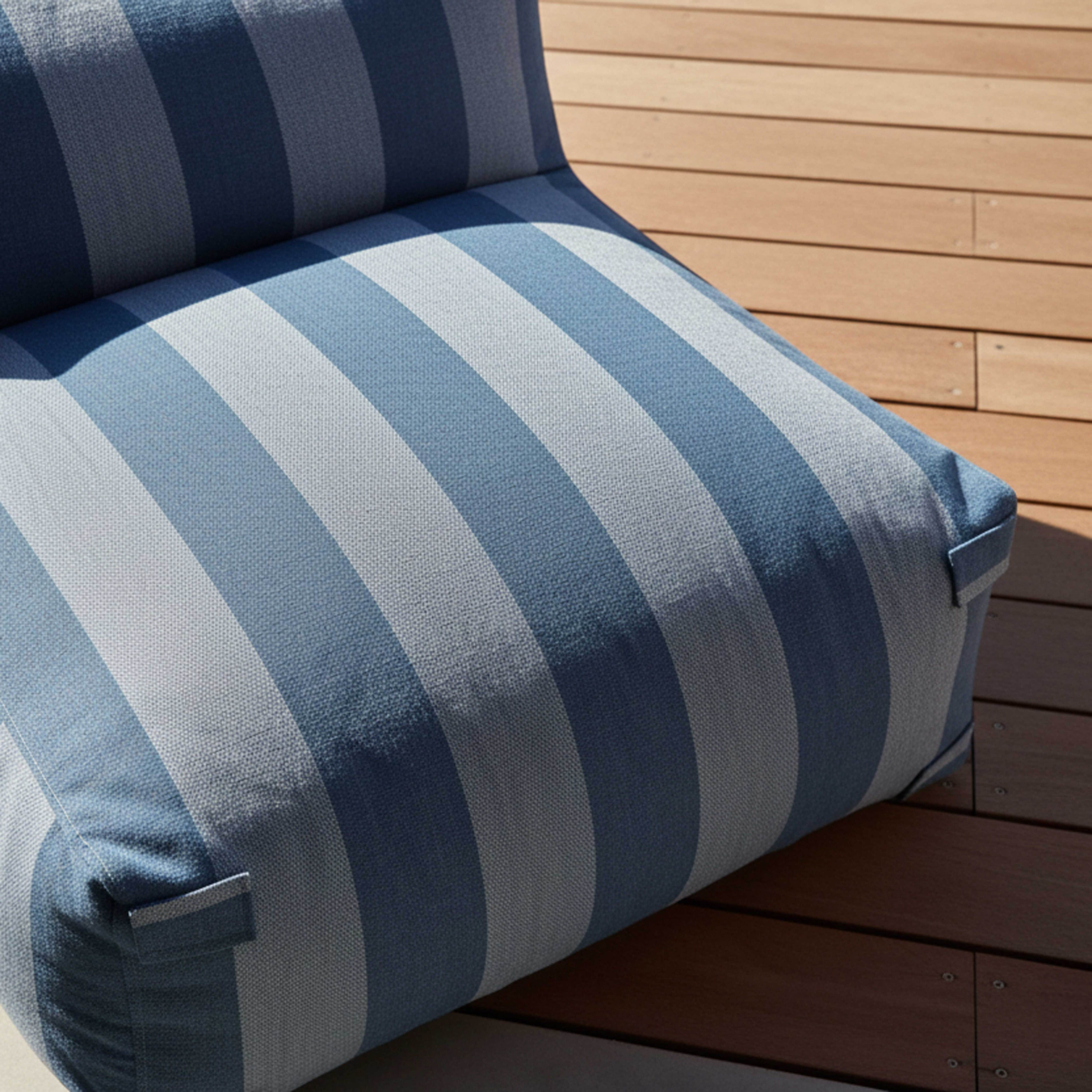 Ein blau gestreiftes Kissen liegt auf einer Holzterrasse.