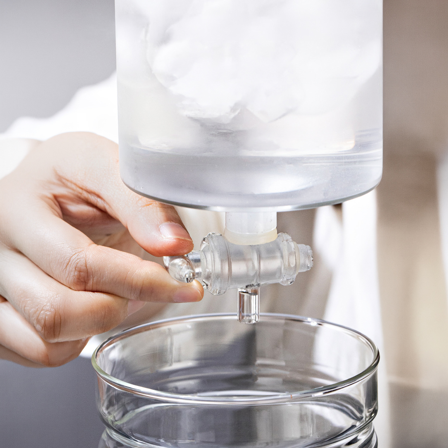 Una mano gira un grifo, dispensando agua en un vaso.