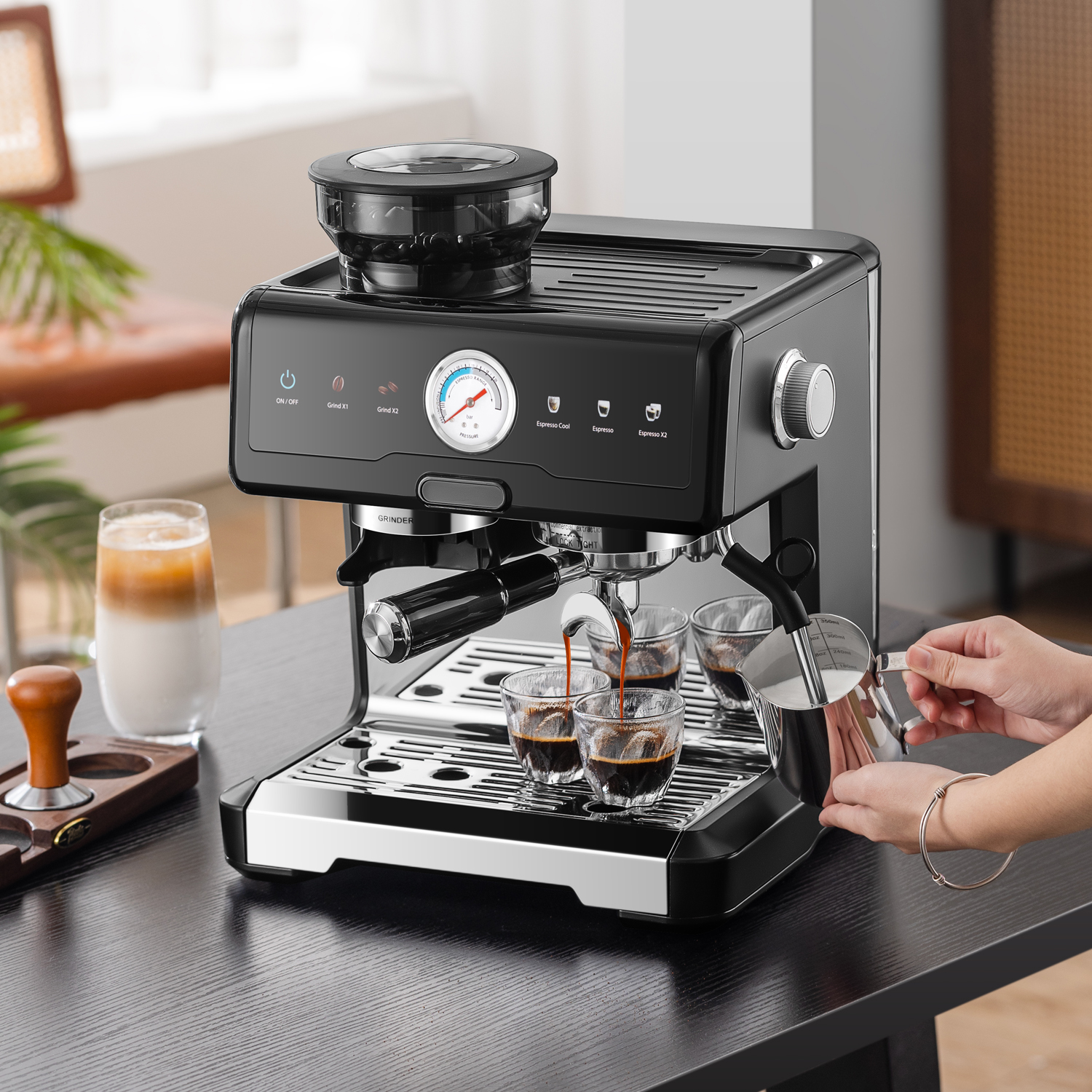 Eine schwarze Espressomaschine mit integriertem Mahlwerk brüht Kaffee in kleine Gläser.