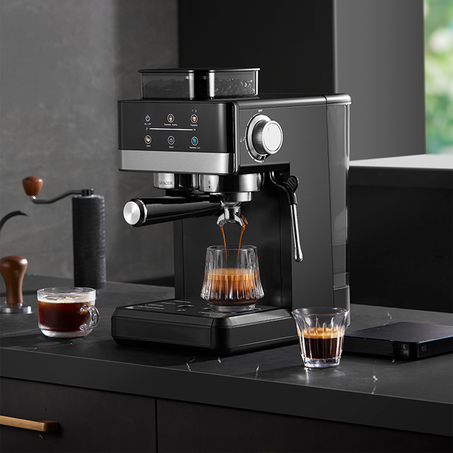 Eine schwarze Espressomaschine brüht Kaffee in ein Glas. Daneben ein weiteres Glas.