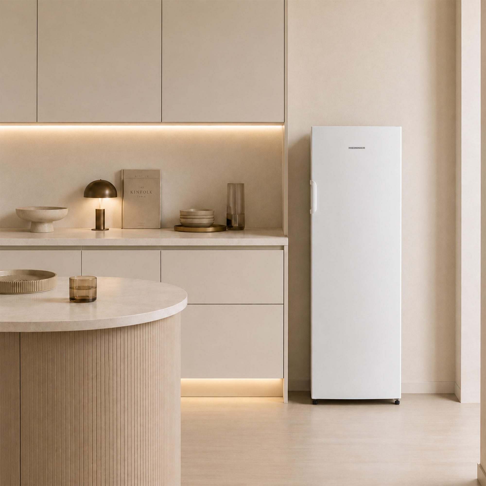 Eine weiße Kühlschrank steht neben einer Küchentheke mit Schränken und einer runden Insel.