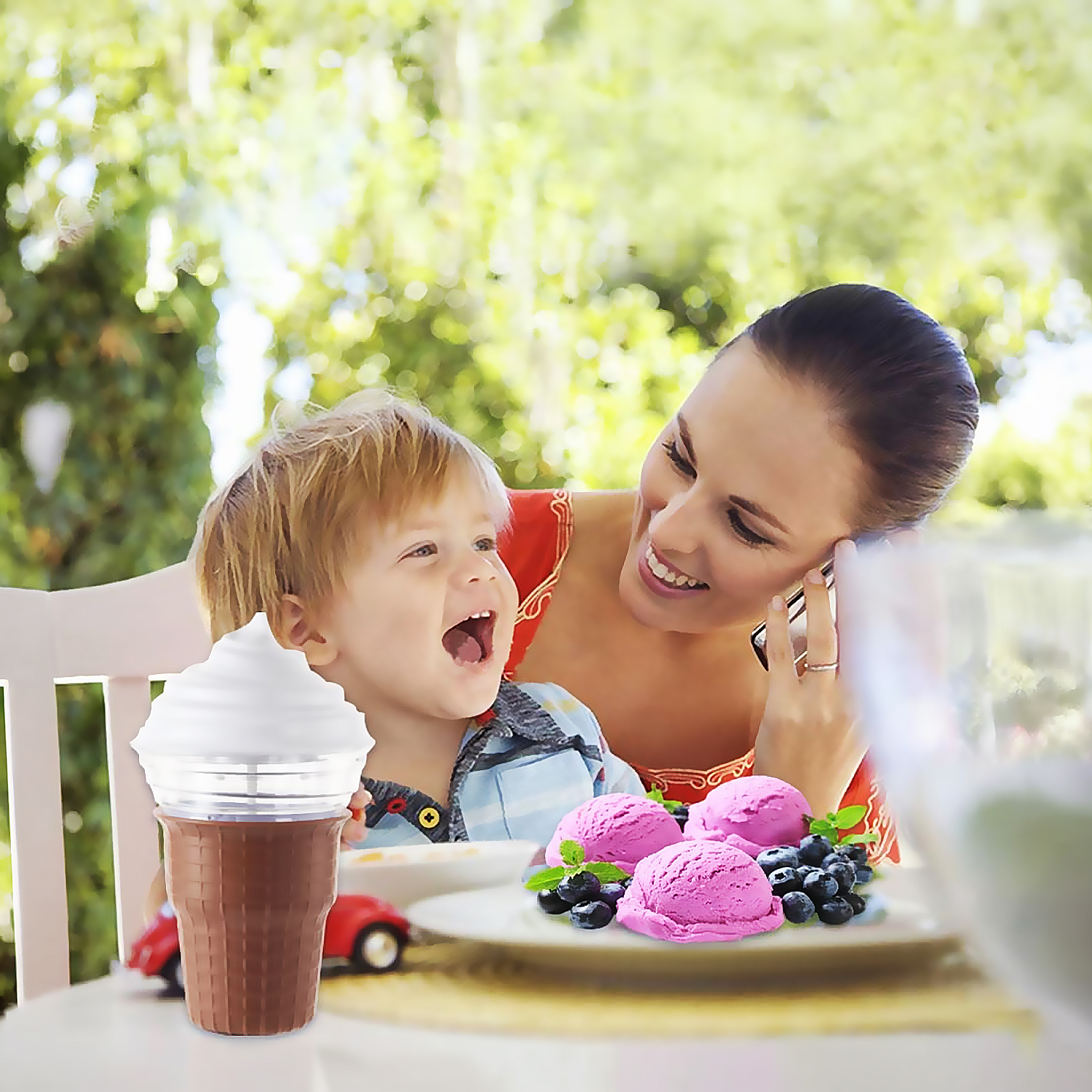 Frau und Kind genießen Eis im Garten. Rosa Eiscreme mit Blaubeeren und Minze.