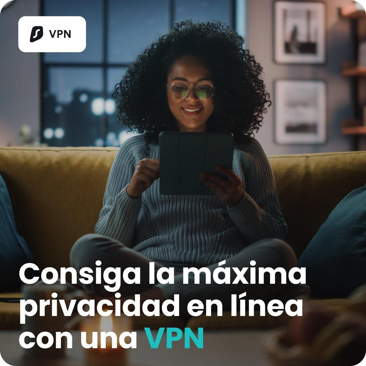 Mujer con pelo rizado mira una tablet sentada en un sofá.