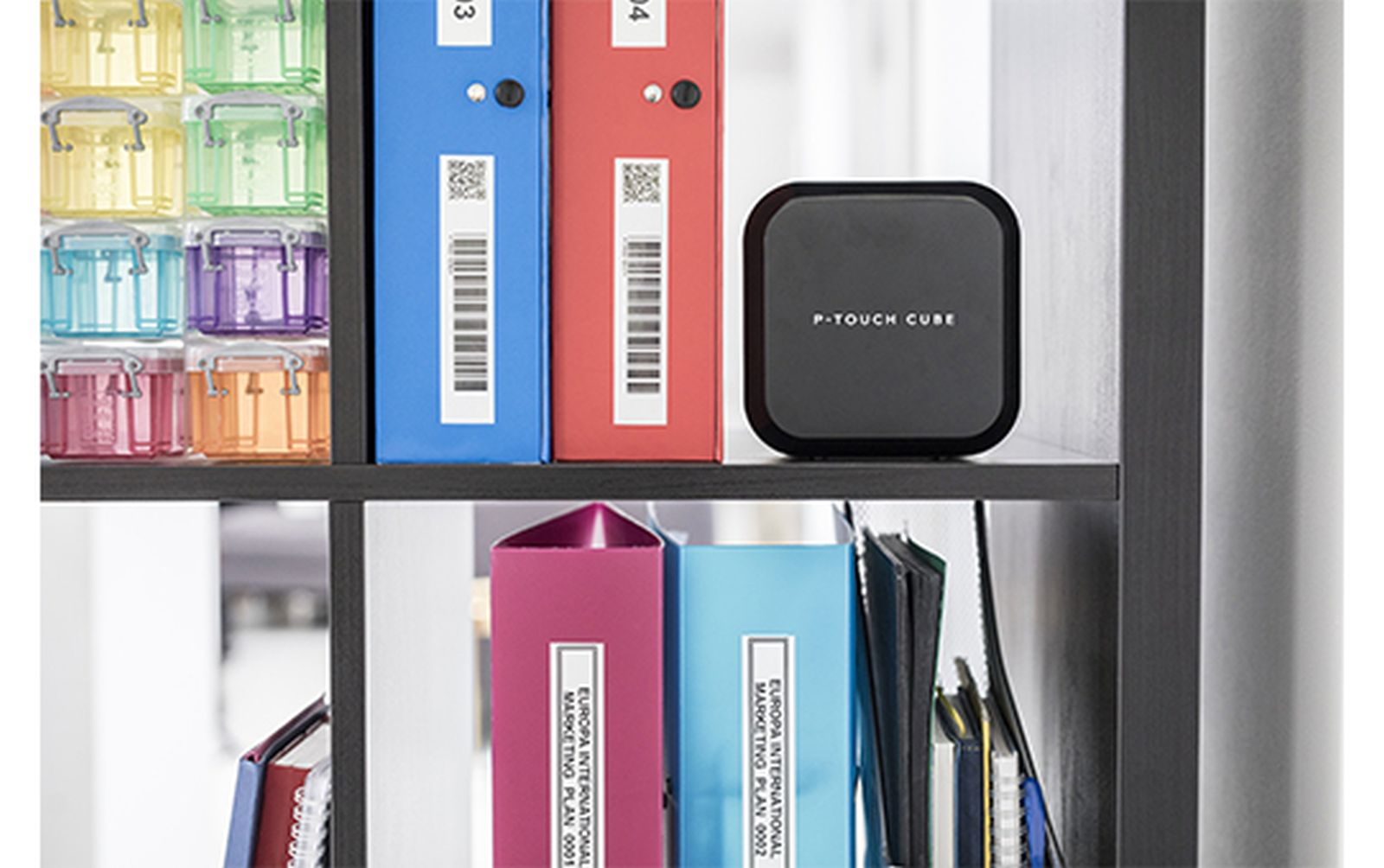 Organisierter Regal mit bunten Aufbewahrungsboxen, Ordnern und einem P-Touch Cube.