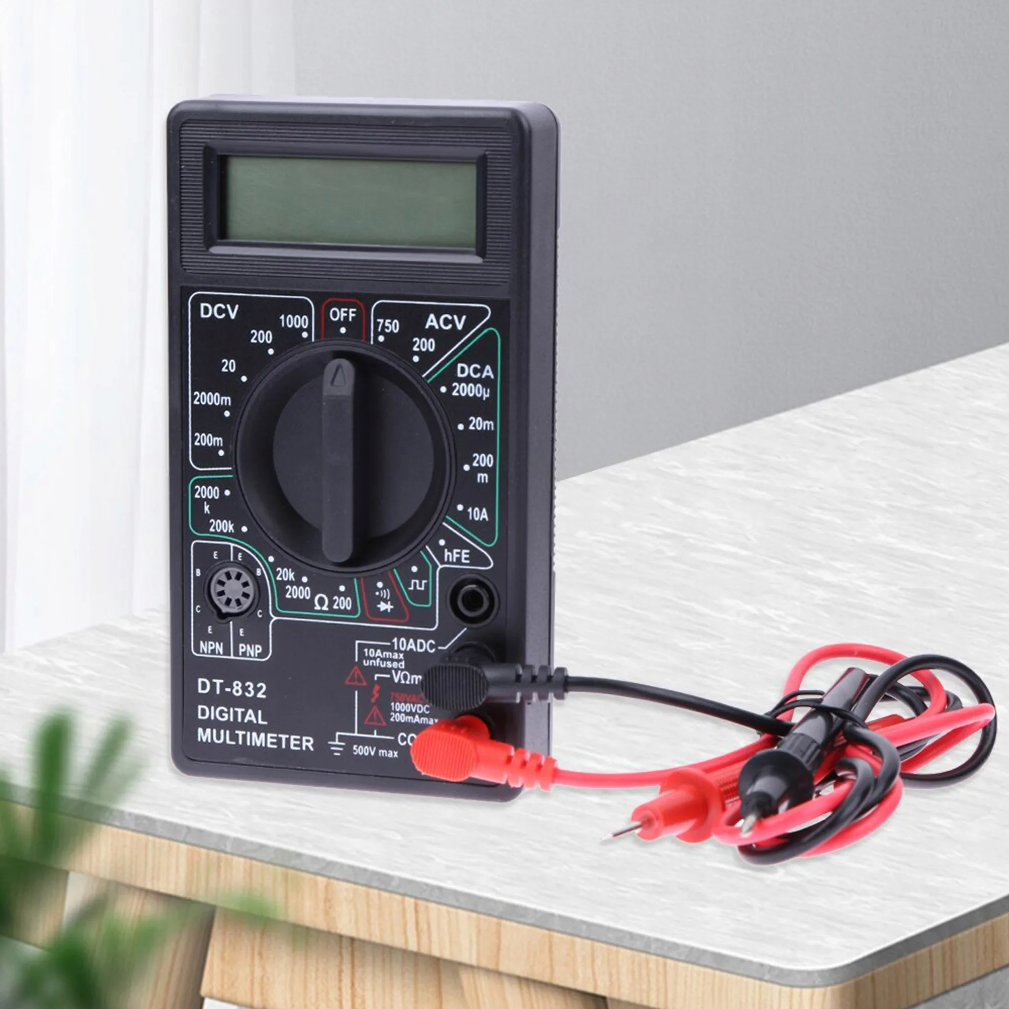 Ein schwarzes Digitalmultimeter mit Messleitungen liegt auf einem Tisch.
