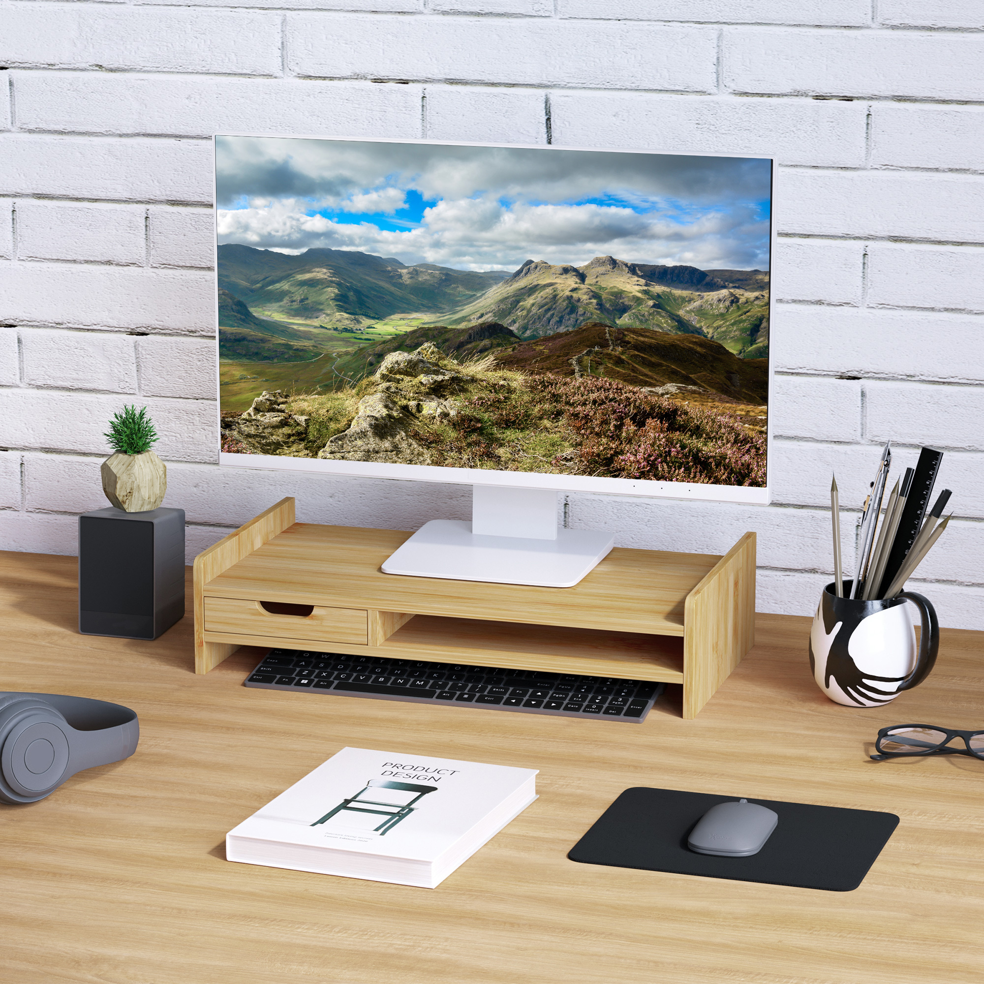 Scrivania con monitor che mostra un paesaggio montano, forniture per ufficio nelle vicinanze.