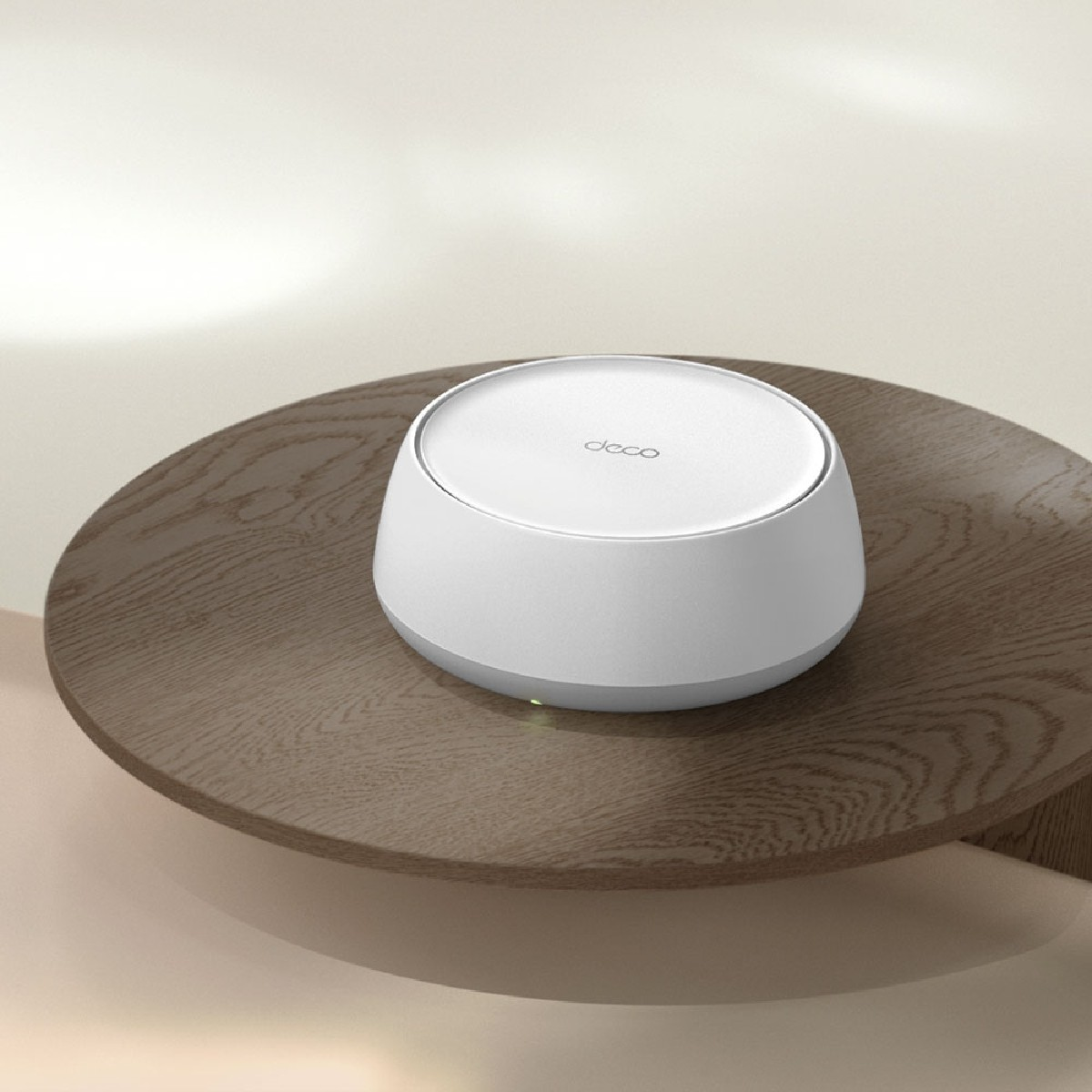 Biały router Deco stoi na okrągłym drewnianym stole.