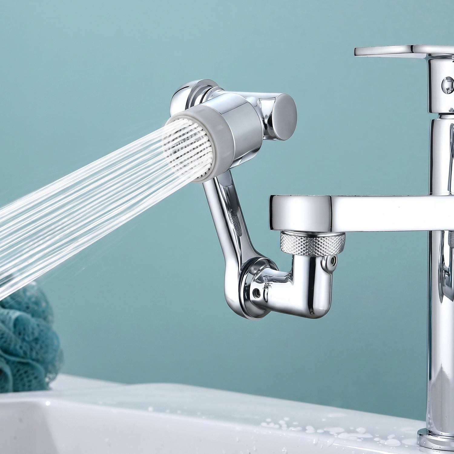 Un accesorio de grifo cromado rocía agua en un lavabo blanco. Se ve una esponja azul.