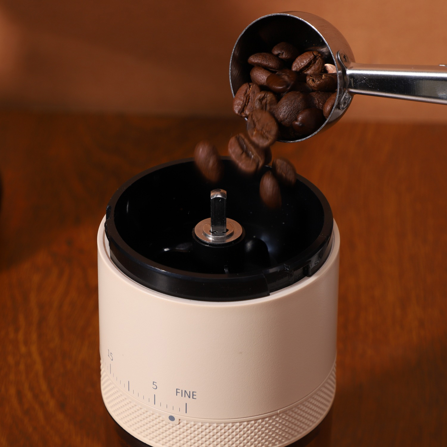 Los granos de café caen de una cuchara a un molinillo.