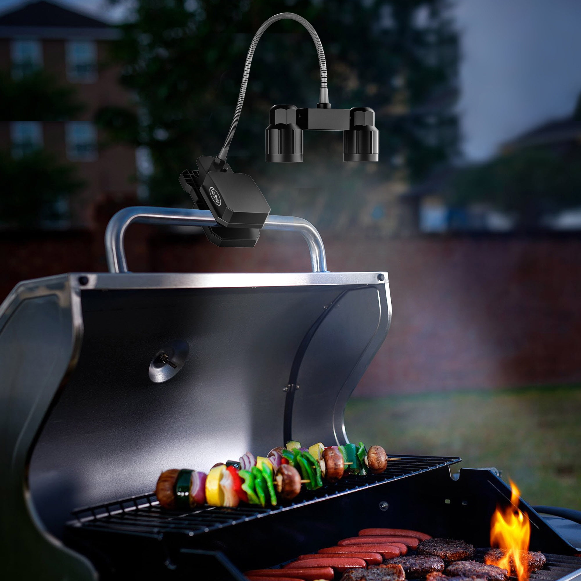 Eine Grillleuchte beleuchtet Burger, Hotdogs und Gemüsespieße, die auf einem Grill garen.