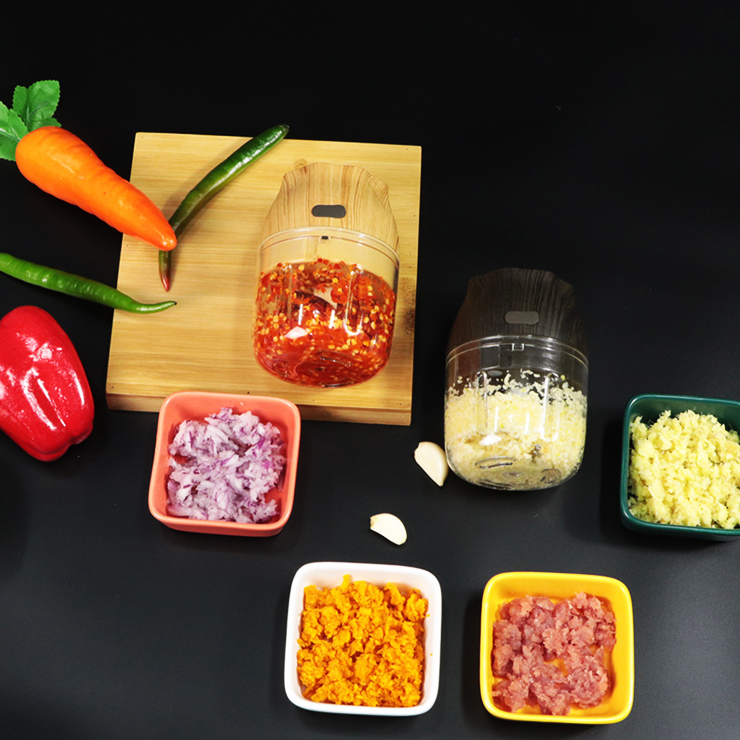 Picadoras de alimentos con verduras, especias y carne picadas sobre fondo negro.