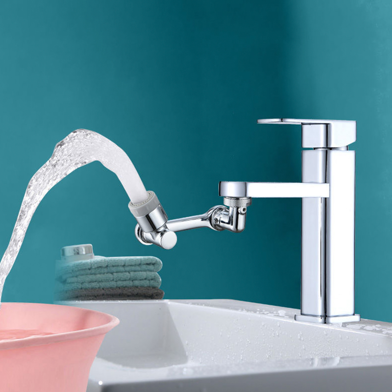 El agua rocía desde una extensión de grifo hacia una palangana rosa junto a toallas dobladas.