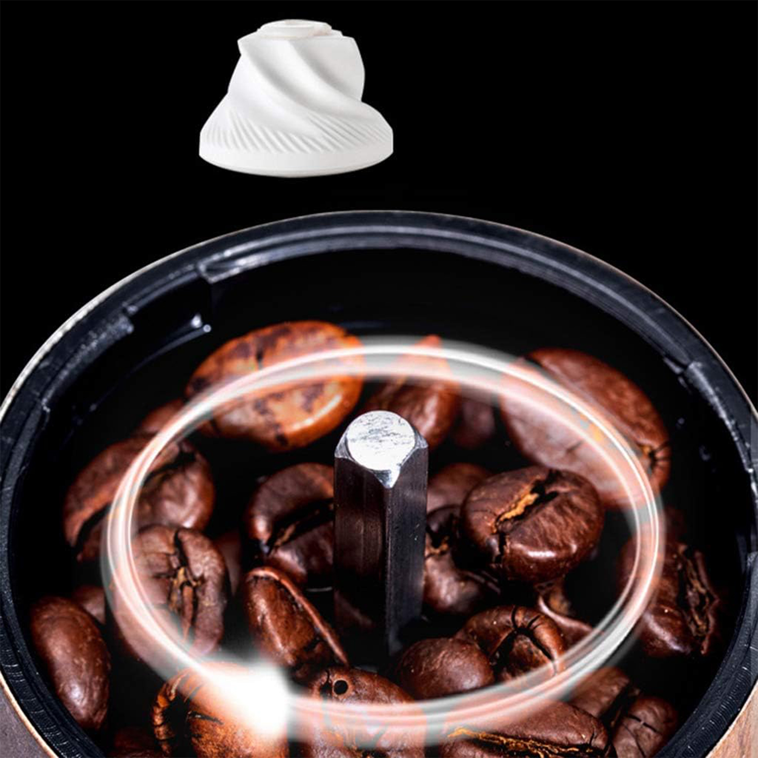 Primer plano de granos de café en un molinillo con una muela cerámica blanca arriba.