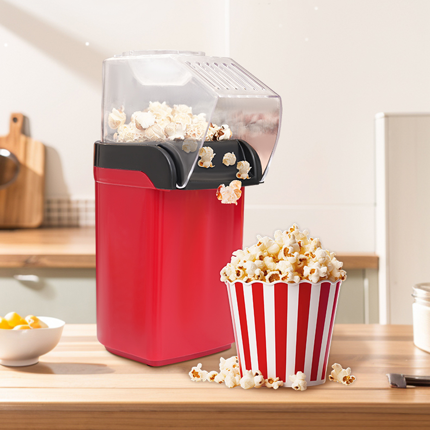 Máquina de palomitas roja con palomitas frescas en un recipiente a rayas al lado.