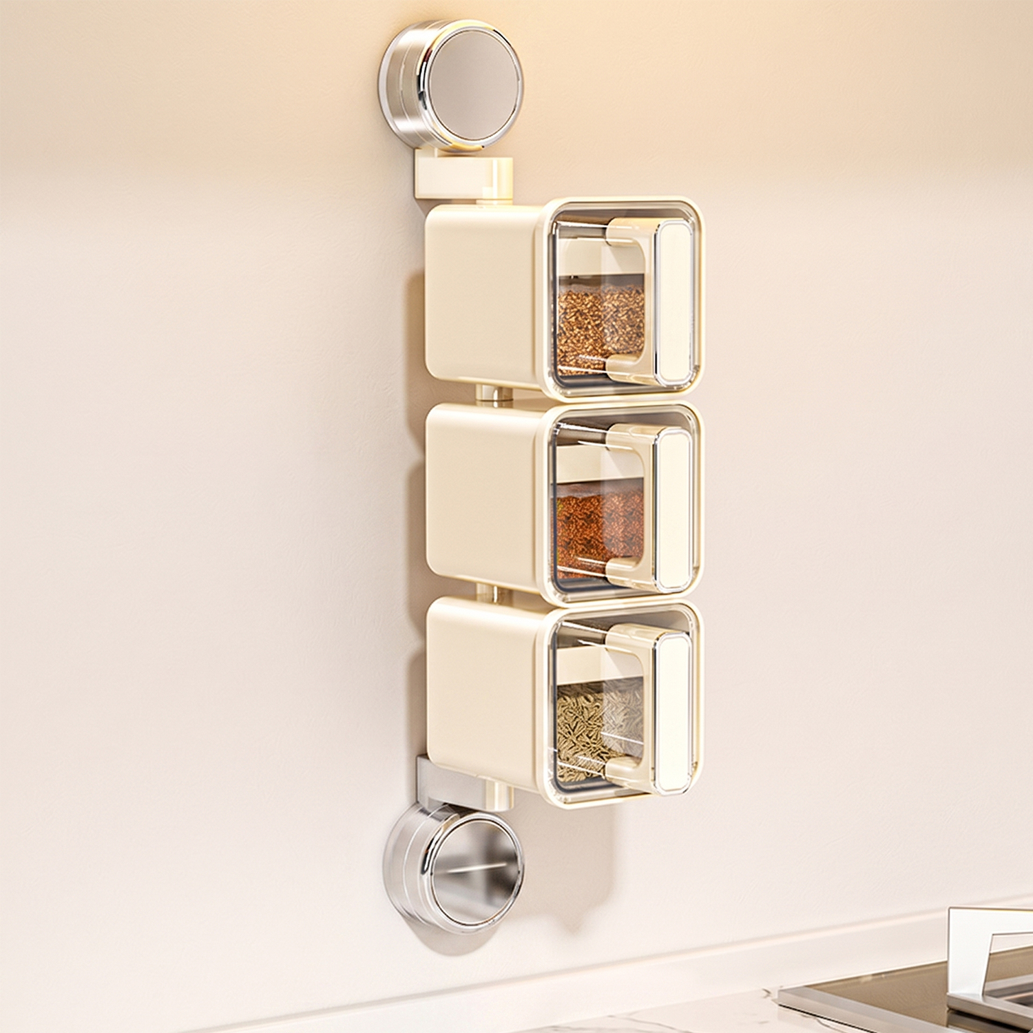 Tre contenitori per spezie color crema montati verticalmente su un muro.