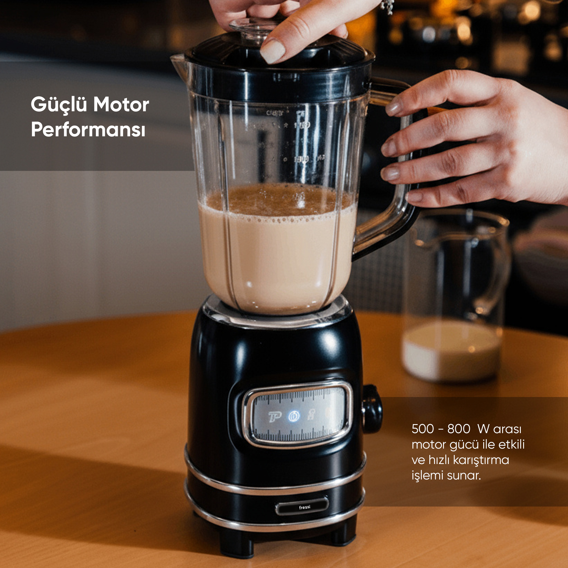 Kişinin kapağını kapattığı siyah blender. Yanında bir sürahi süt duruyor.