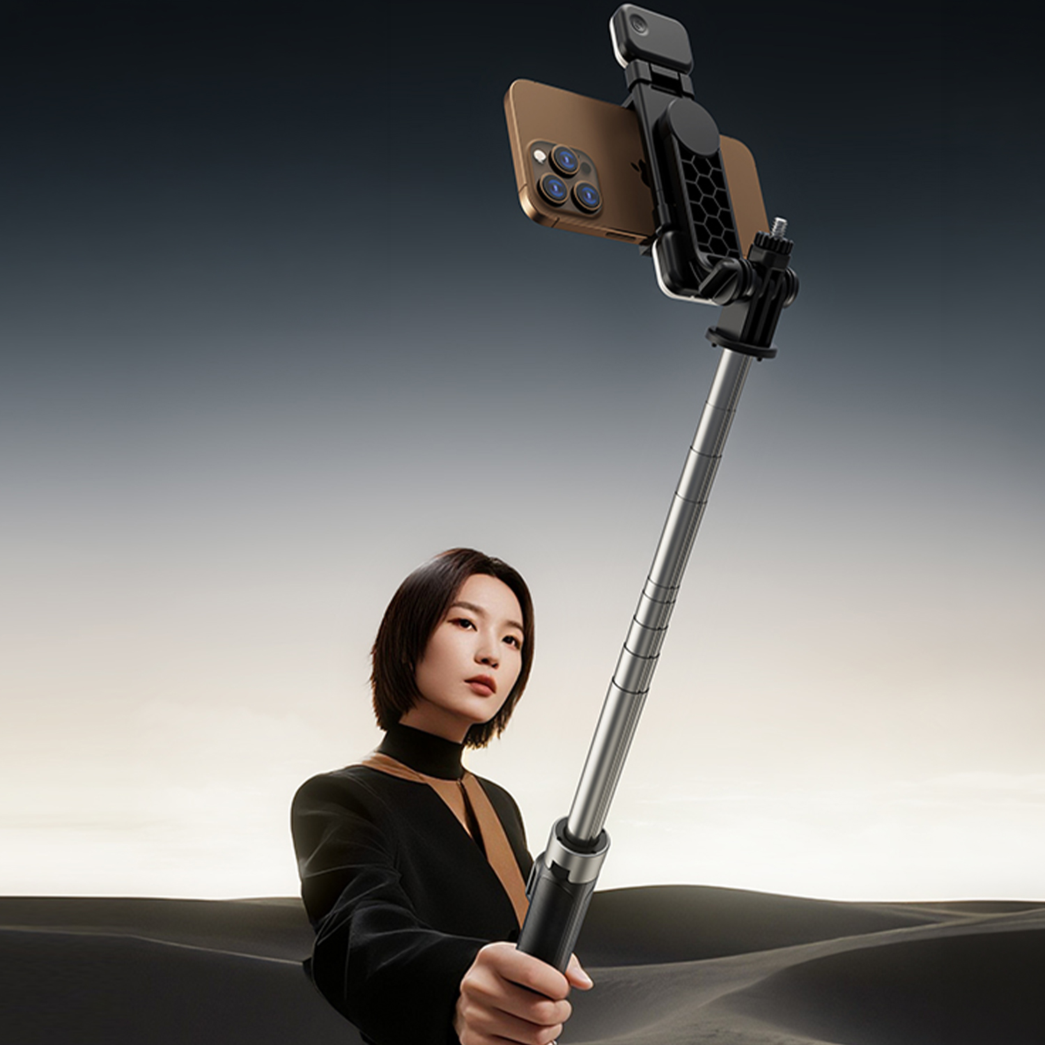 Frau hält Selfie-Stick mit Handy in Wüstenlandschaft. Goldene Stunde Himmel.