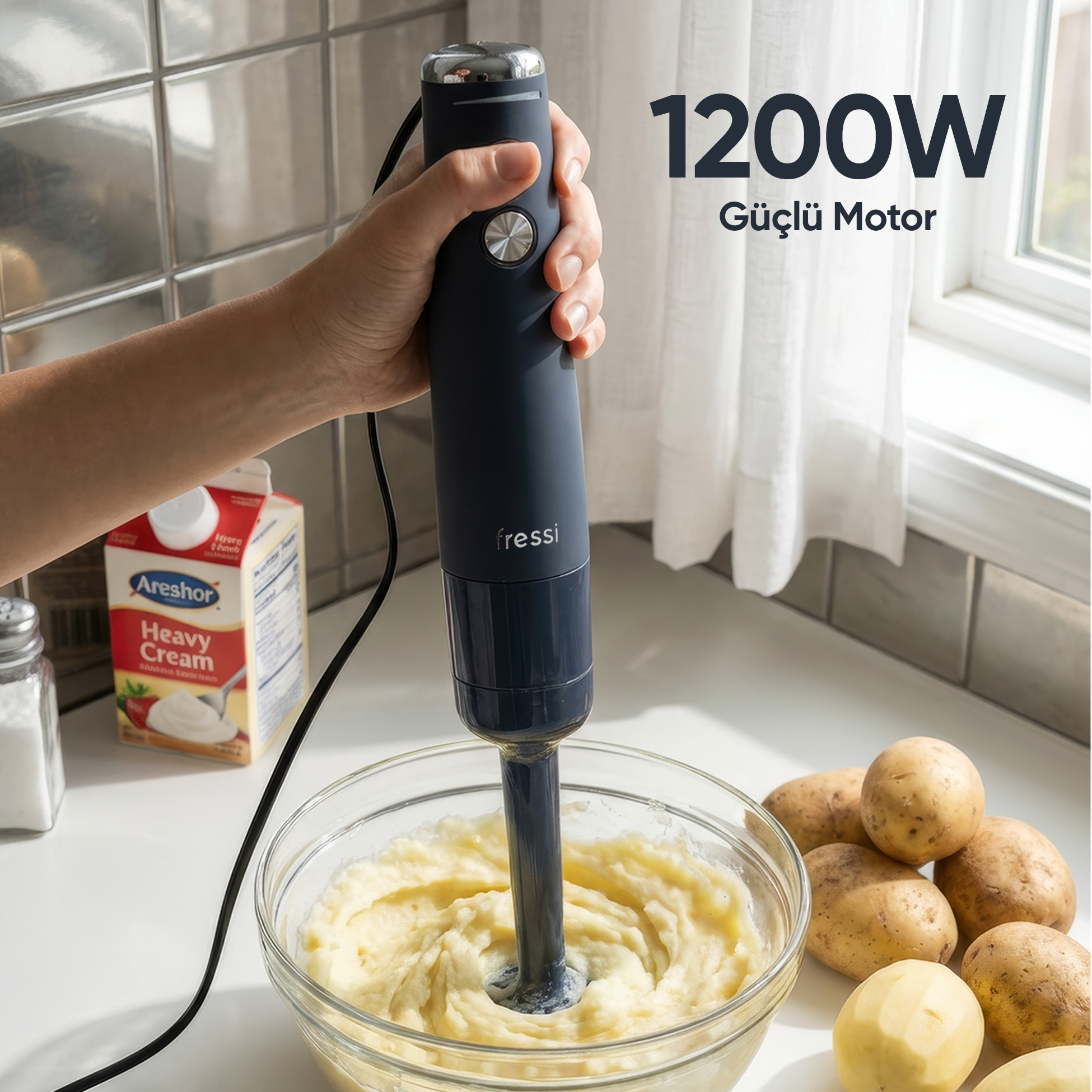 Bir el, bir kase patates püresinin üzerinde koyu renkli el blenderı tutuyor.