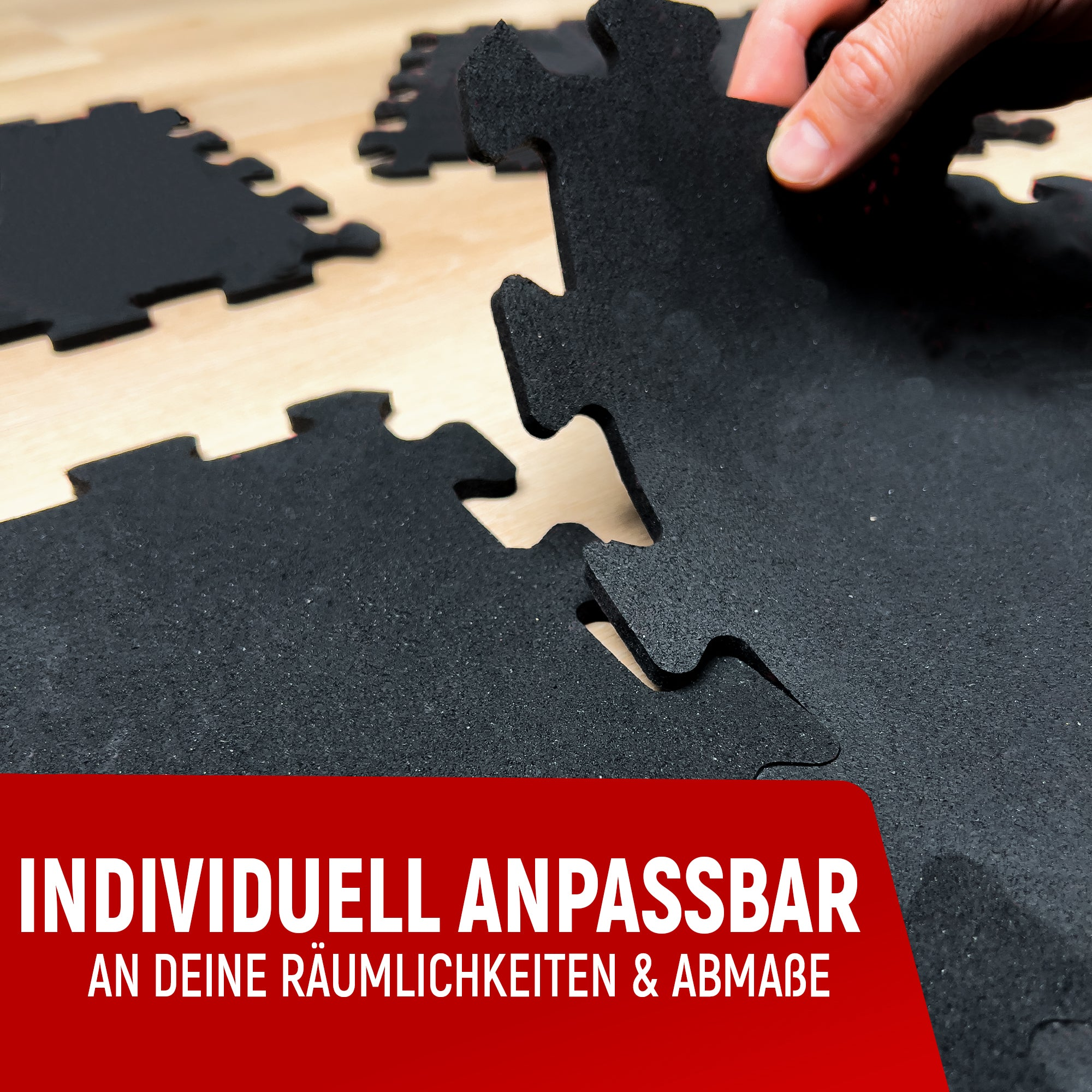 Schwarze Puzzle-Bodenmatten werden auf einem Holzboden zusammengefügt.