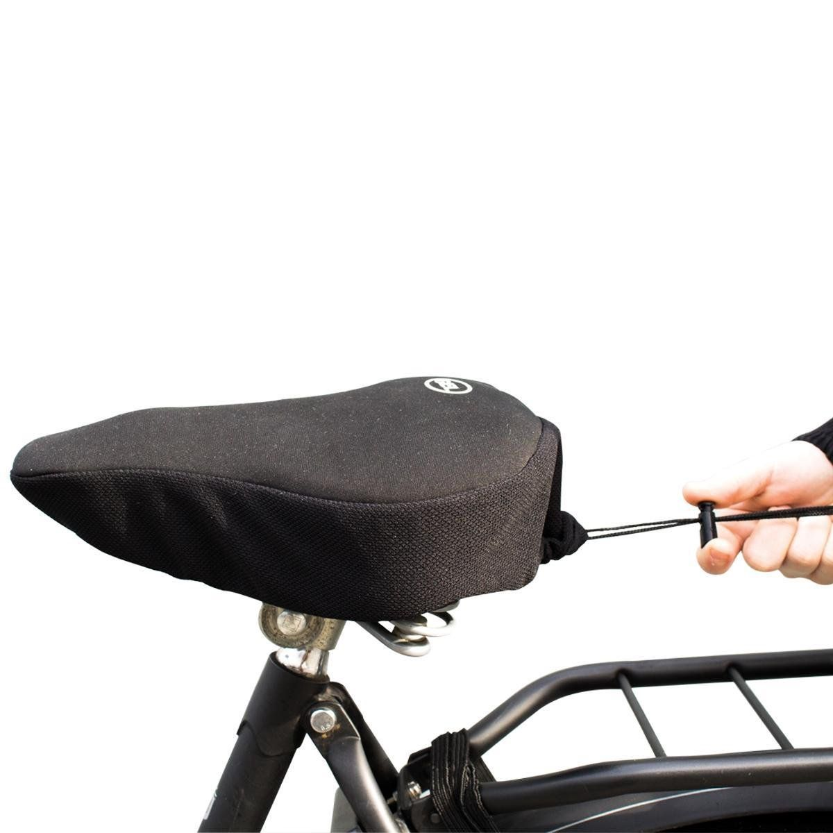 Een zwarte fietszadelhoes met trekkoord wordt door een hand vastgemaakt.