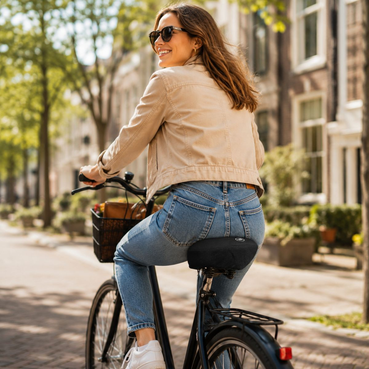 Vrouw met zonnebril fietst op een straat met bomen en gebouwen.