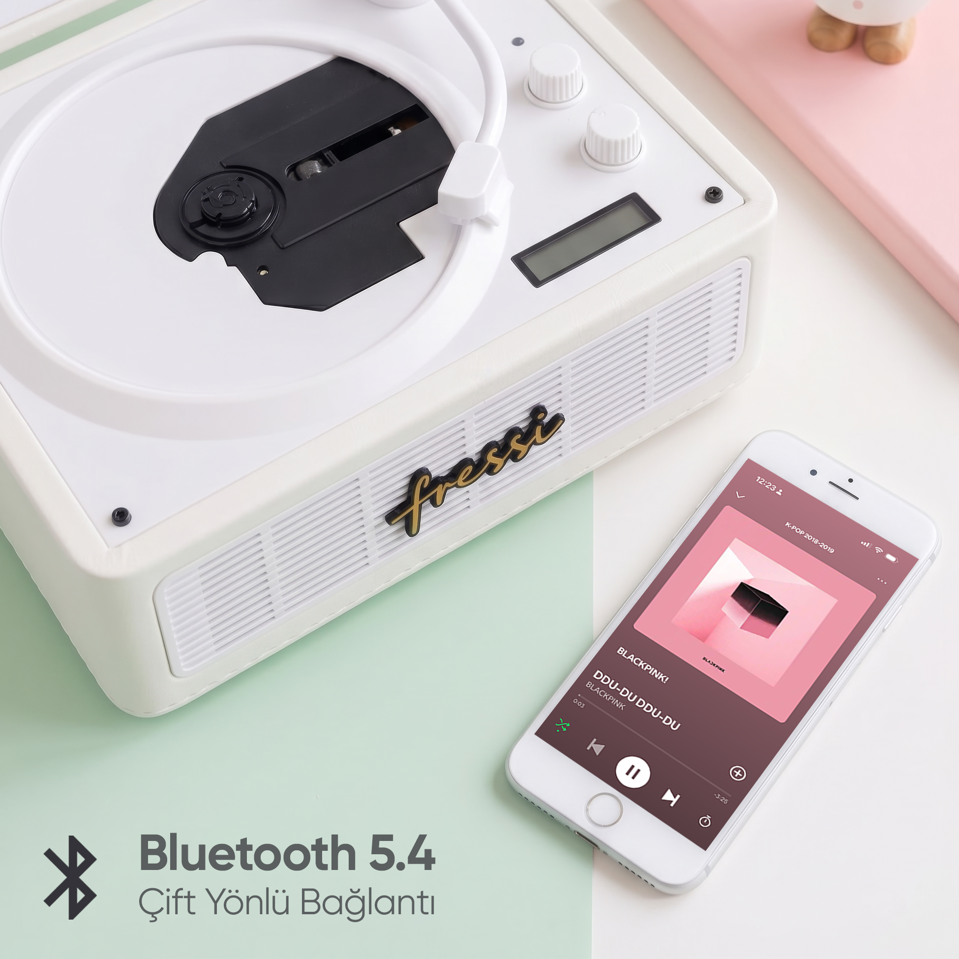 CD yuvalı beyaz pikap, yanında müzik uygulaması olan bir akıllı telefon.