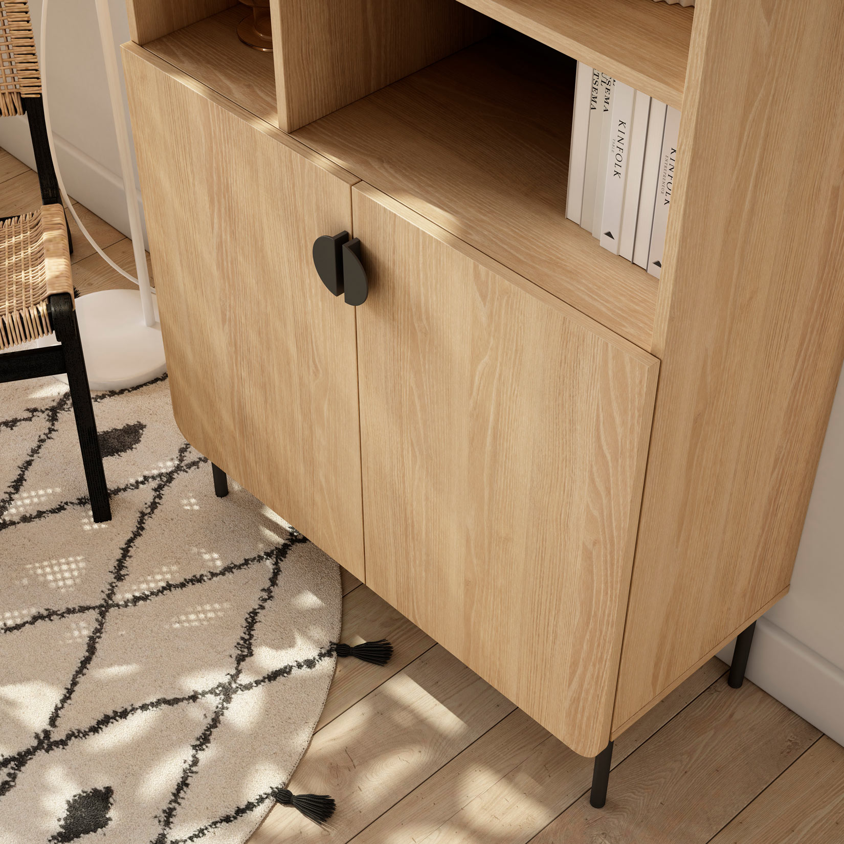Un mueble de madera clara con tiradores negros, junto a una silla y alfombra.