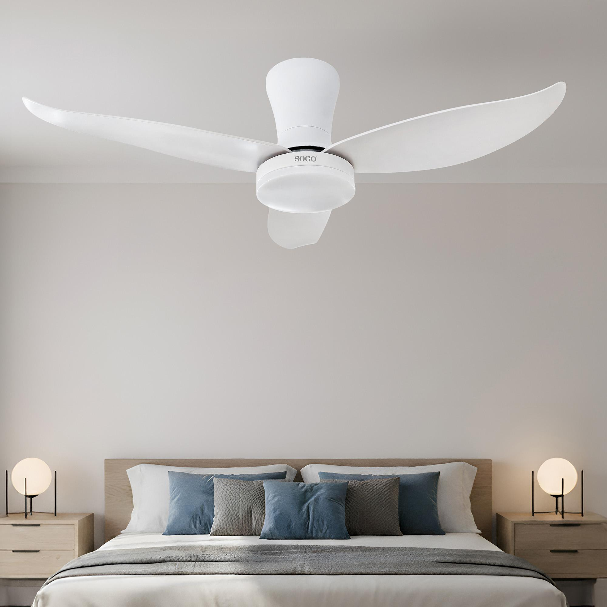 Un ventilatore da soffitto bianco sopra un letto con cuscini blu e grigi.