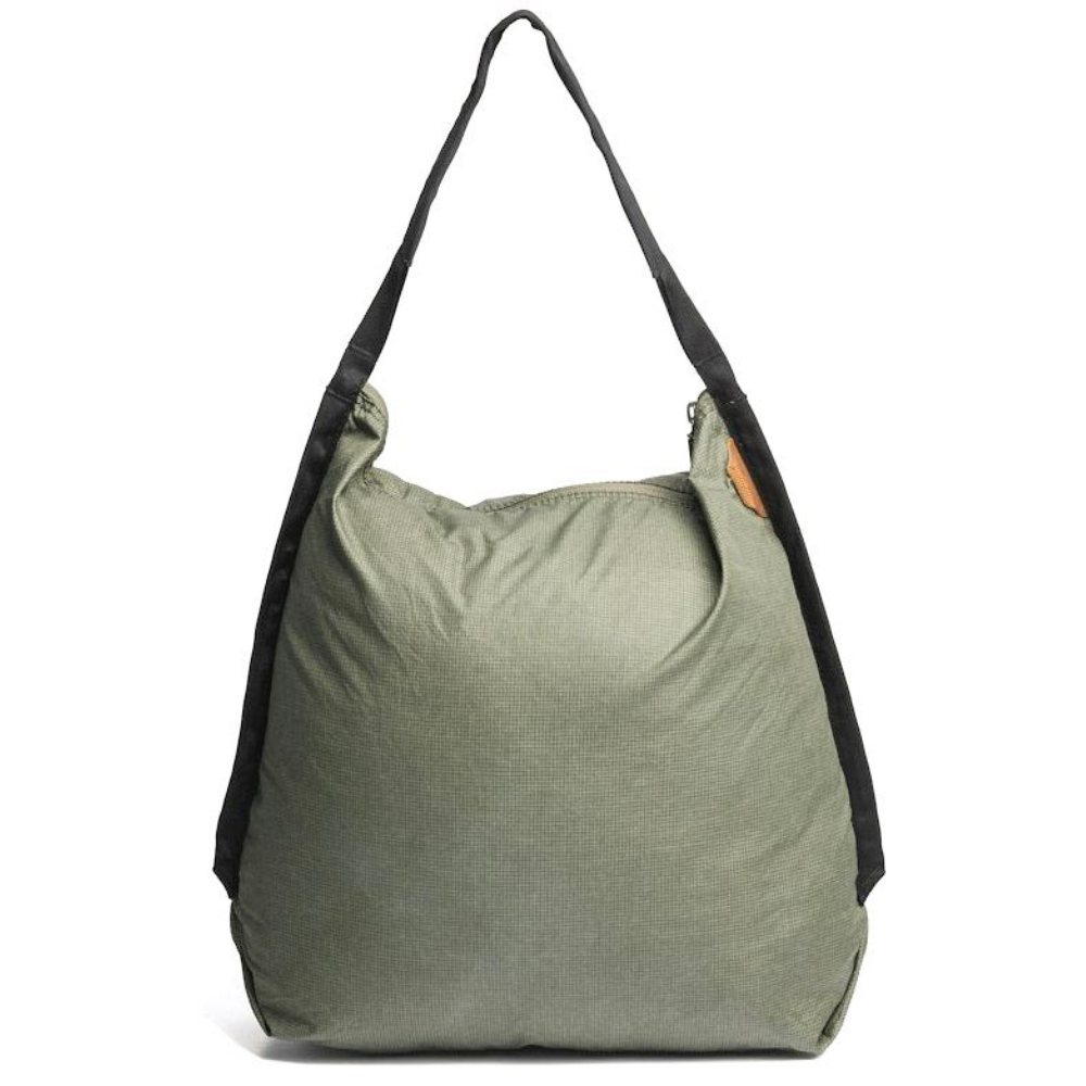 Een olijfgroene stoffen tas met zwarte hengsels, geïsoleerd op een witte achtergrond.