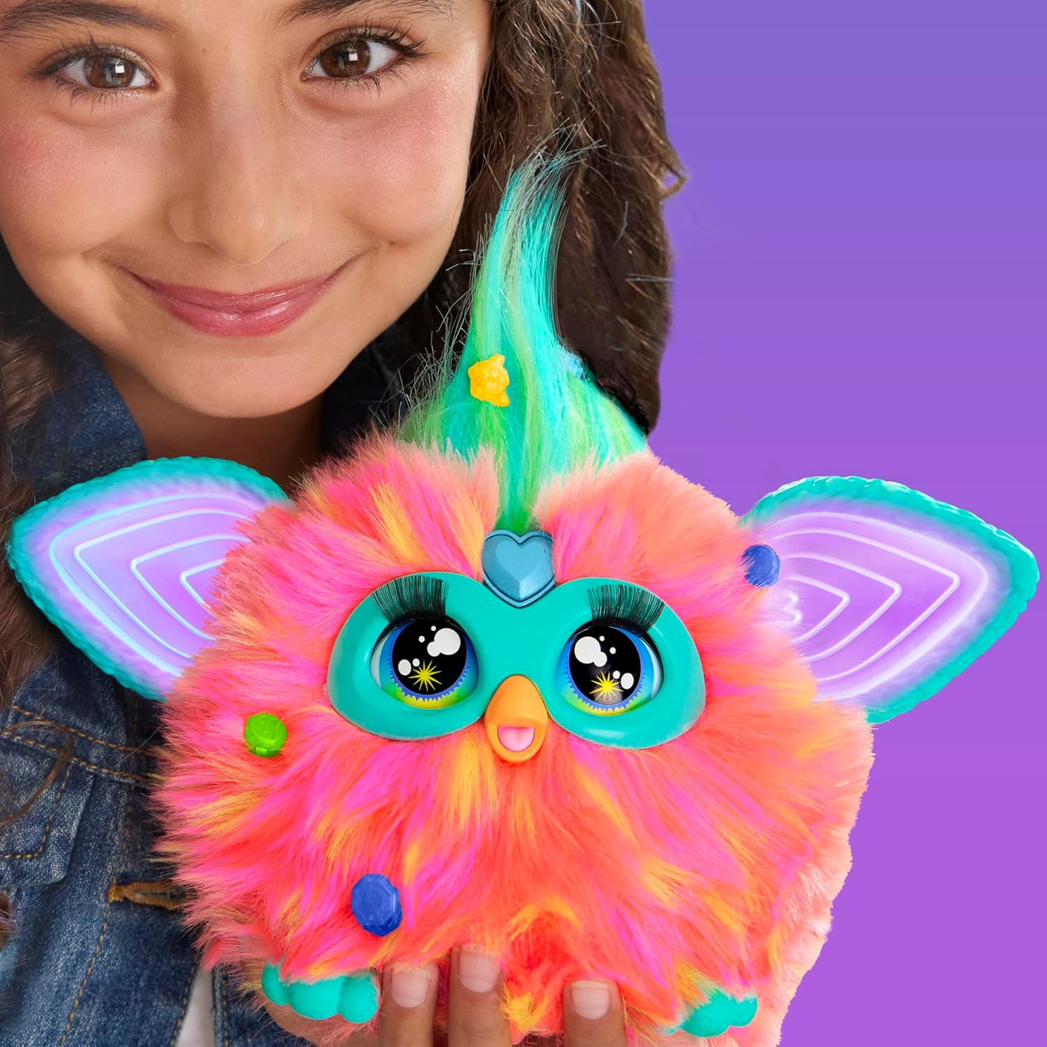 Ein Mädchen hält ein leuchtendes, pelziges Spielzeug mit bunten Haaren und großen Augen.