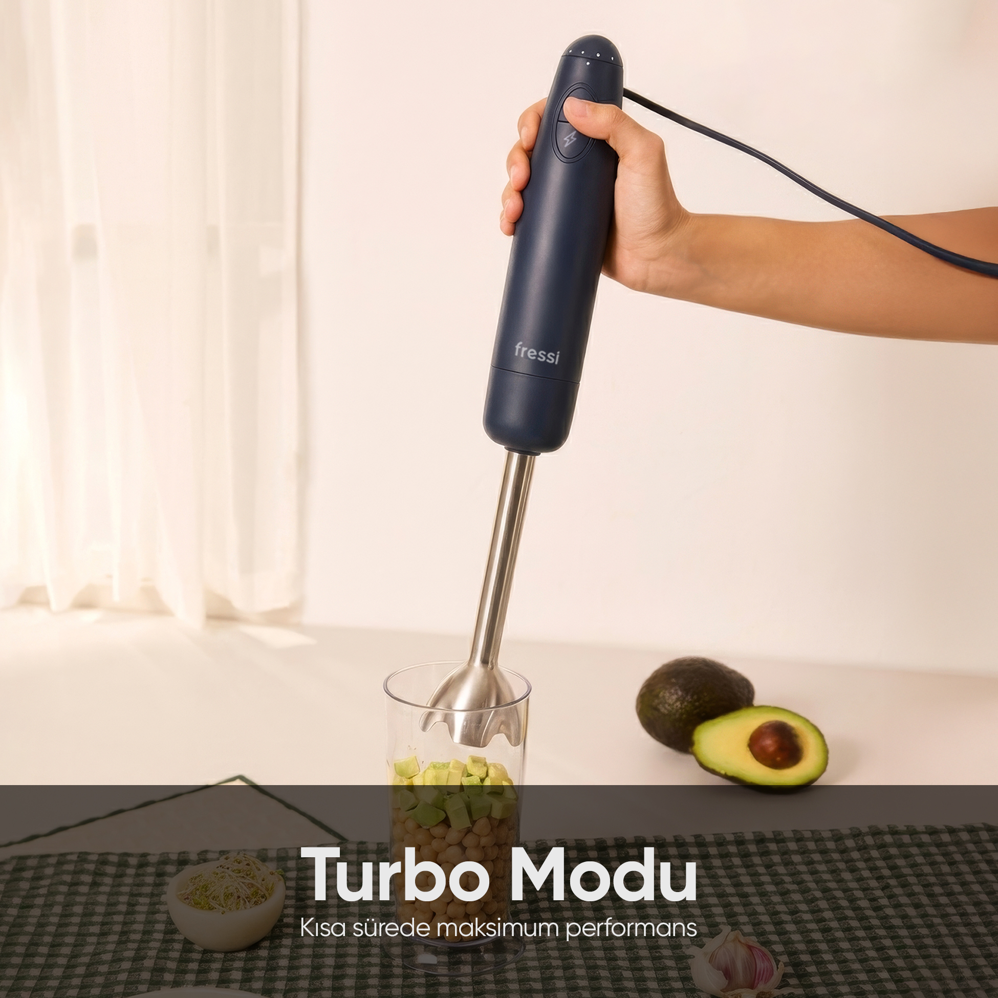 Bir el, bir bardak nohut ve avokadonun üzerinde koyu renkli el blenderı tutuyor.