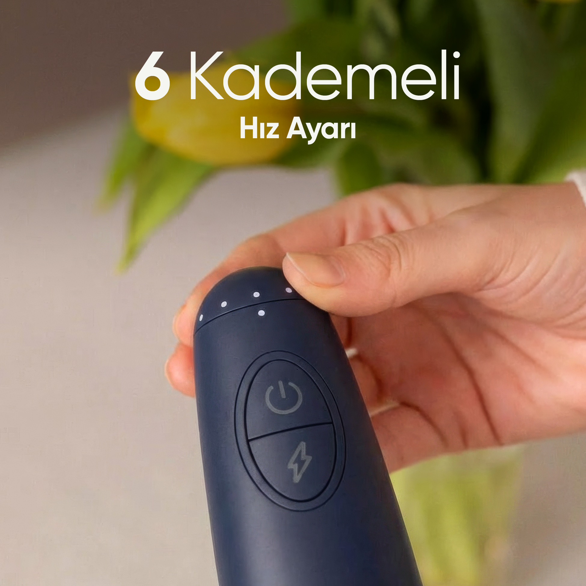 Bir el, güç ve hız simgeleri olan koyu mavi bir cihaz tutuyor. Arkada sarı laleler.