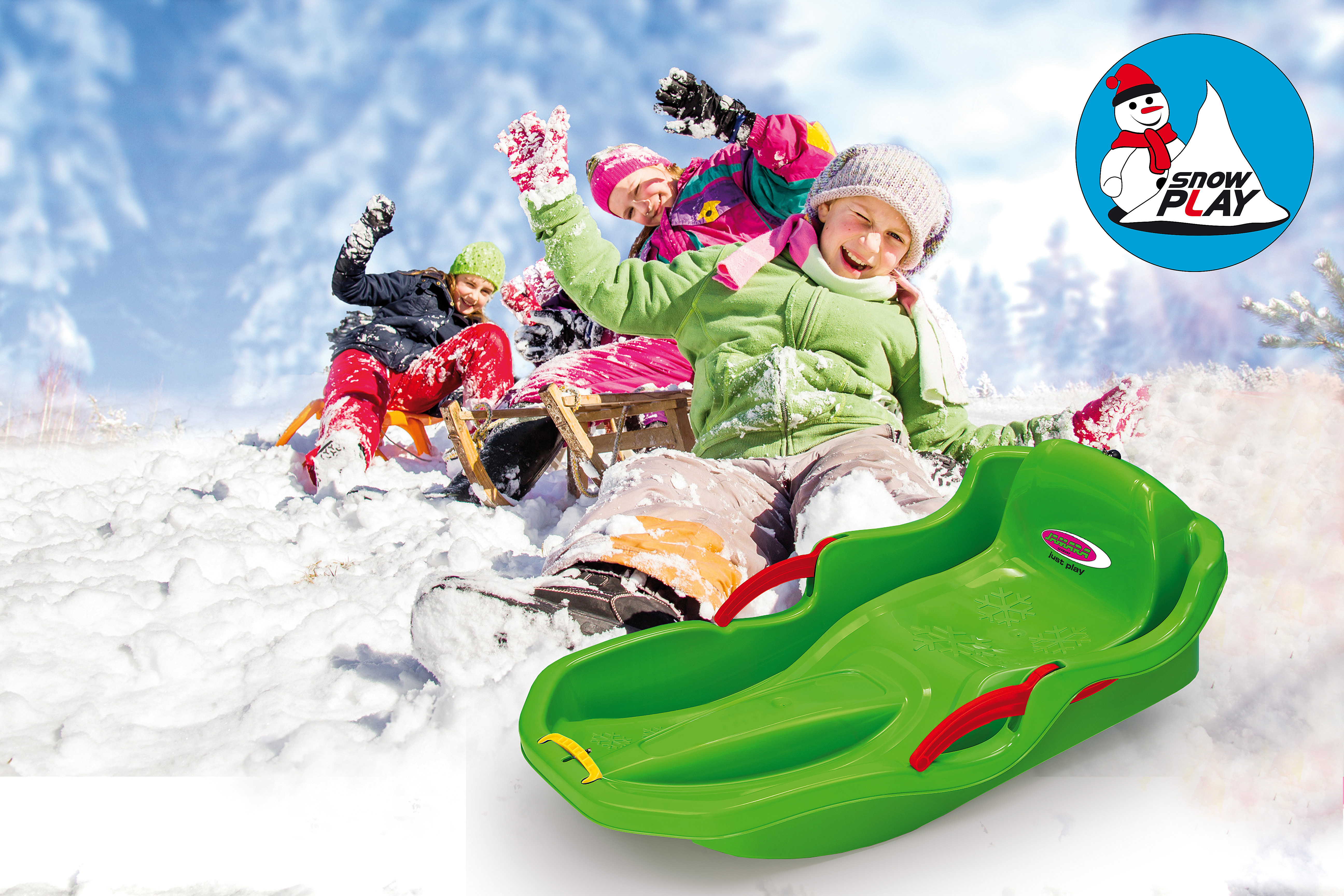 Bambini slittano sulla neve con una slitta verde, circondati da alberi.
