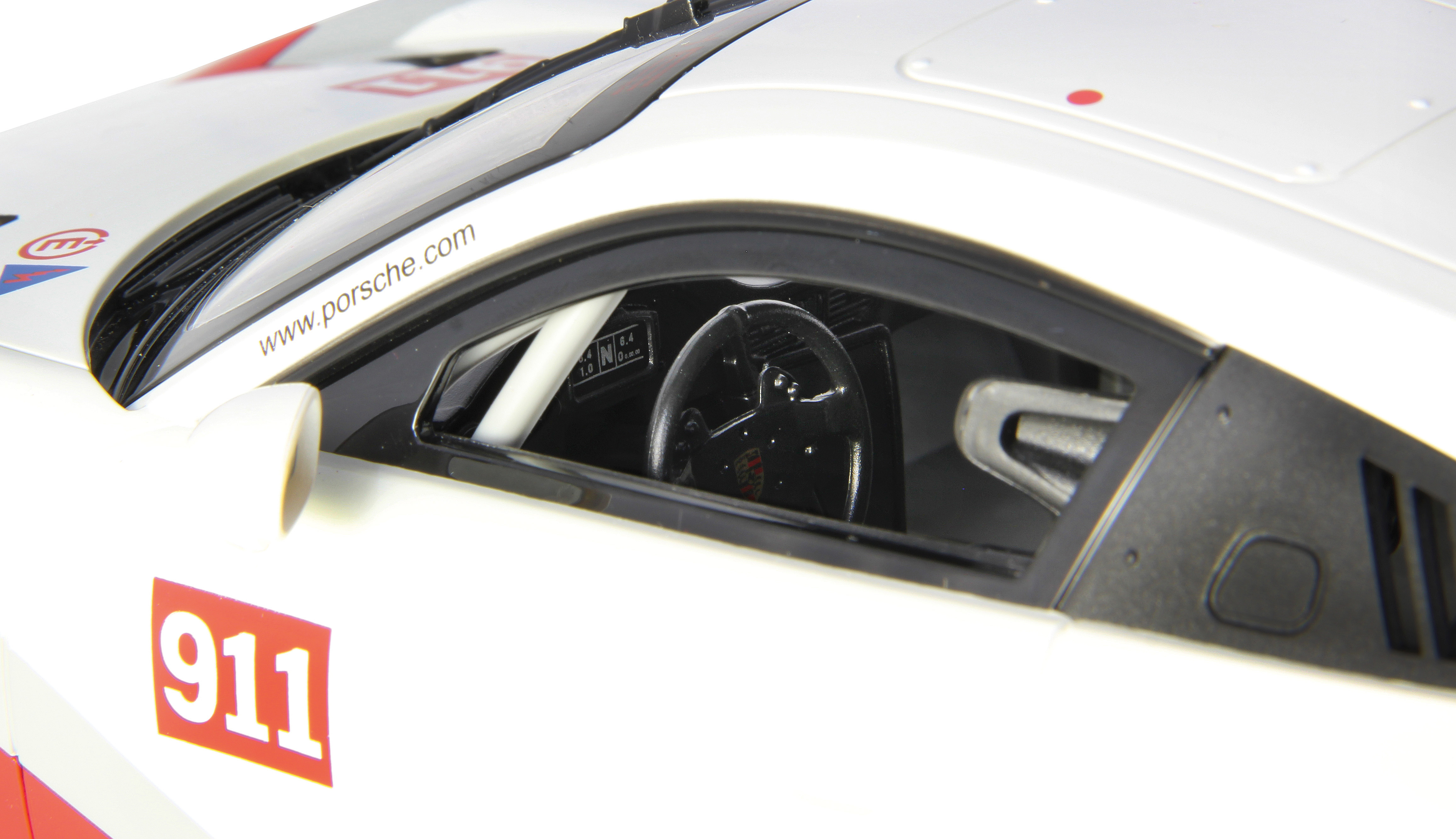 Detailaufnahme eines weißen Porsche 911-Rennwagens mit rotem Aufkleber.