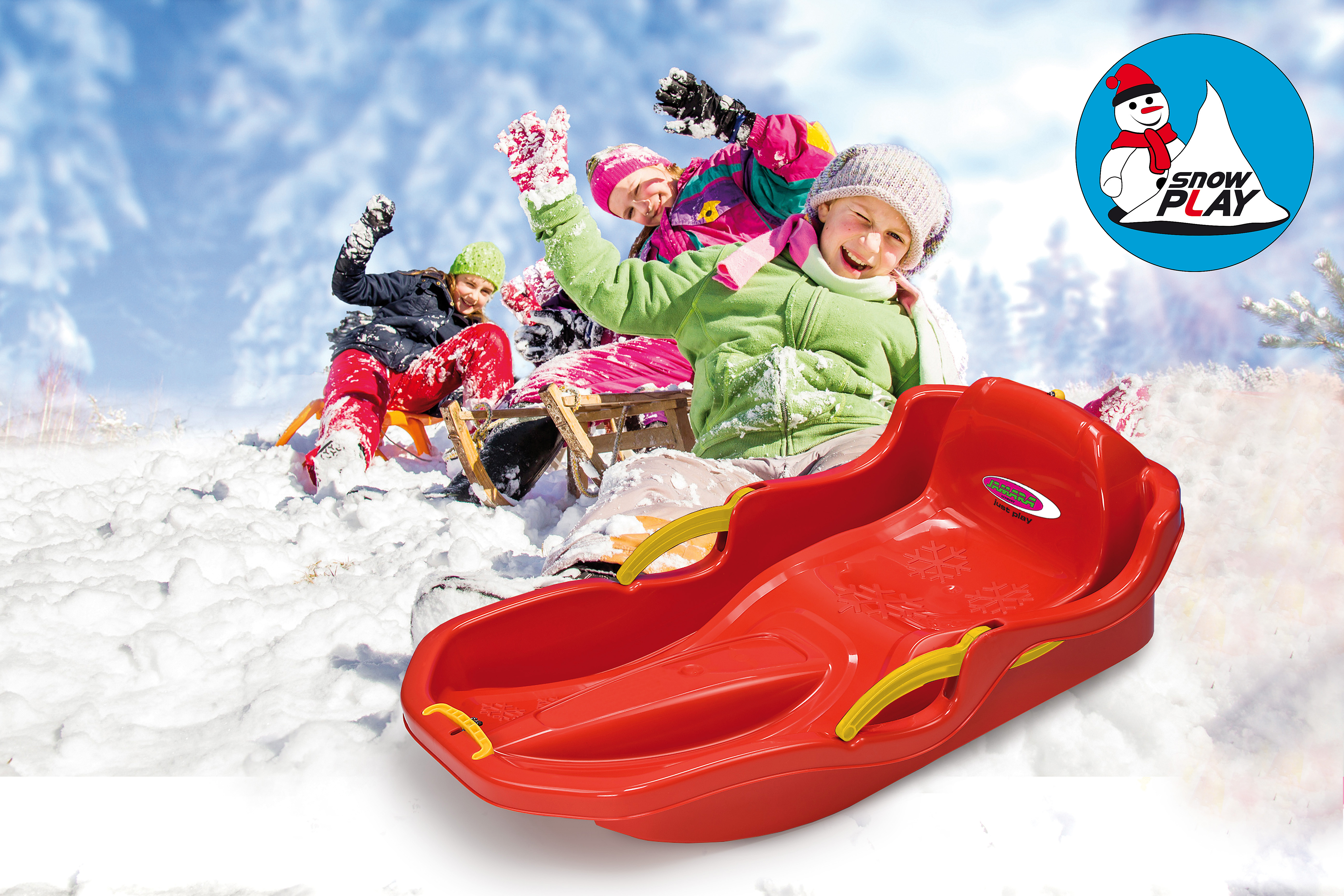 Bambini che scendono in slittino sulla neve con una slitta rossa in primo piano.