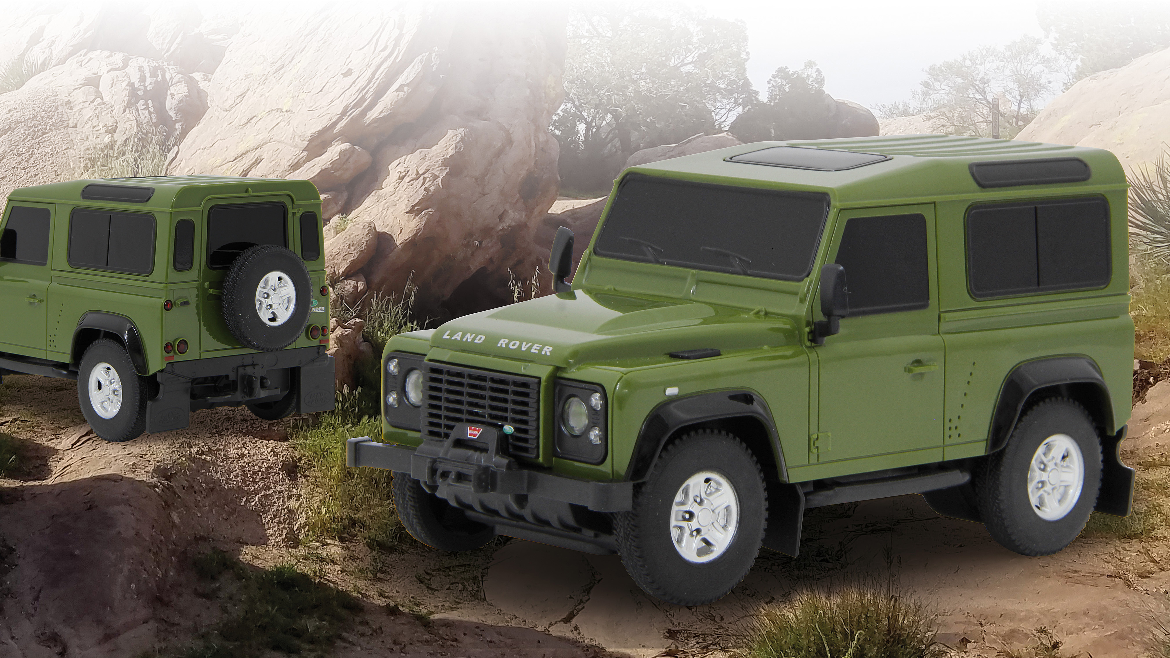 Dos Land Rover Defender de juguete verdes en terreno rocoso desértico.