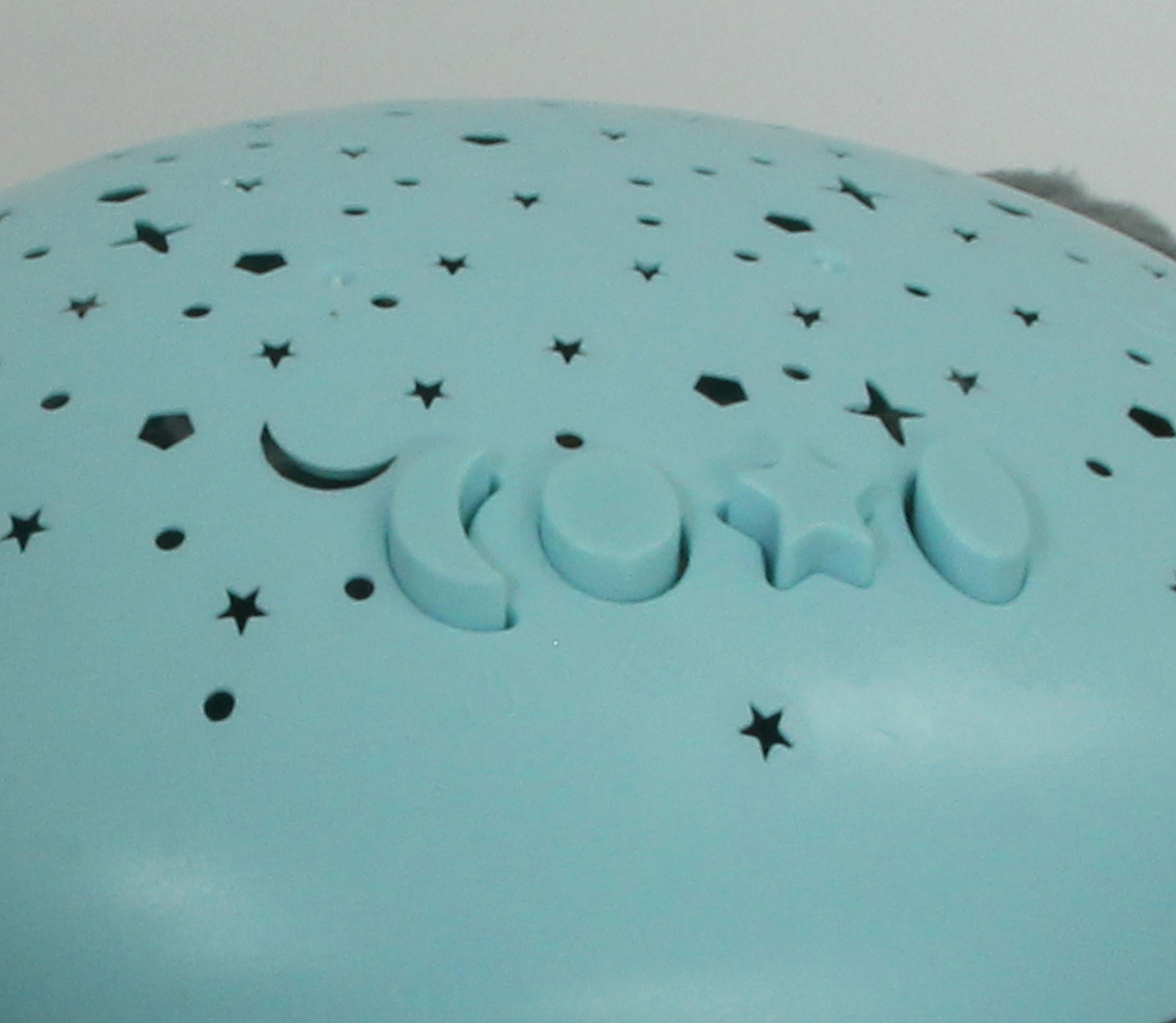 Eine hellblaue Lampe mit ausgestanzten Sternen und Monden. Es gibt auch die Buchstaben 'COCO'.