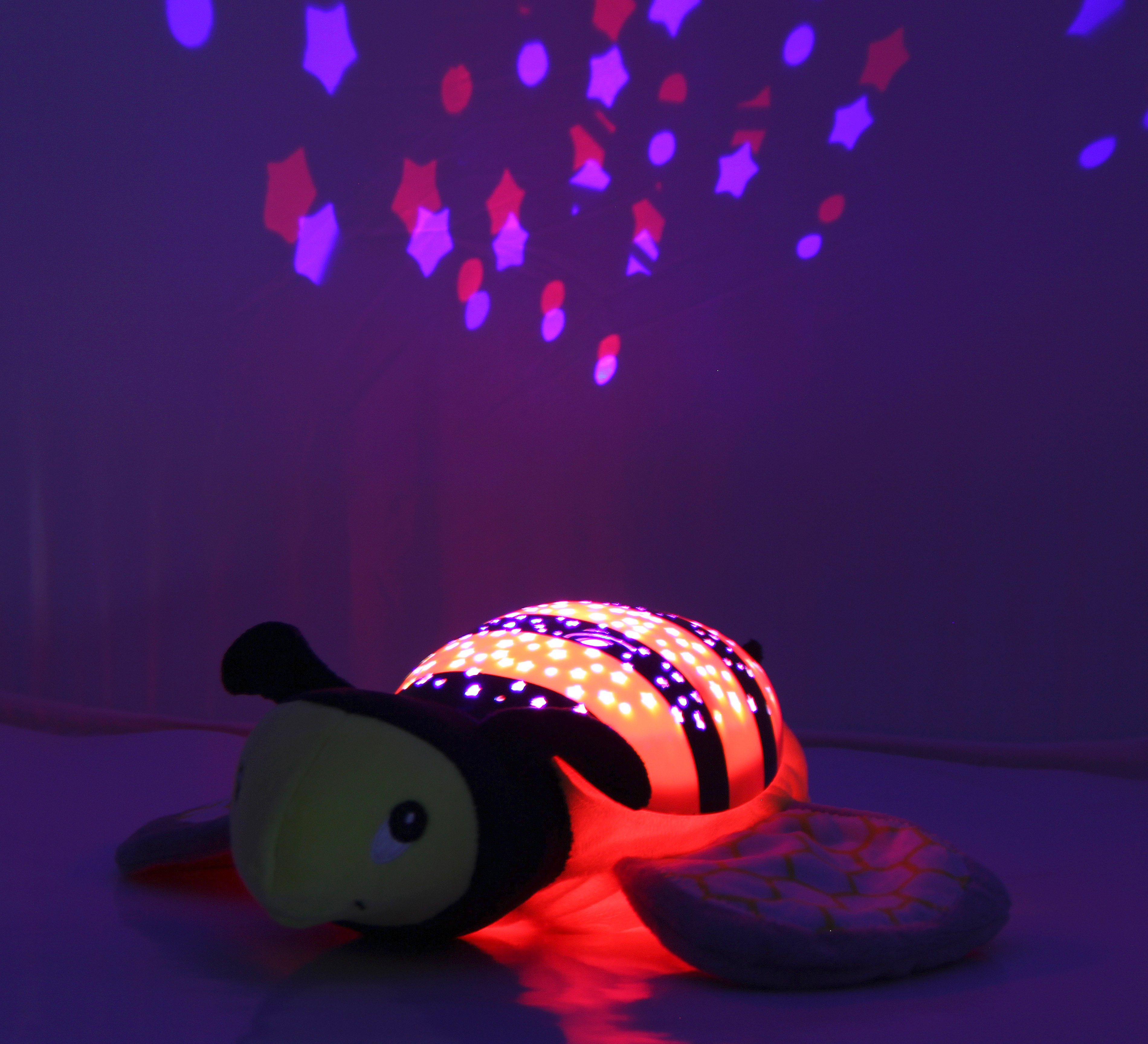 Ein leuchtender Bienen-Nachtlichtprojektor mit Sternenmuster auf dem Hintergrund.