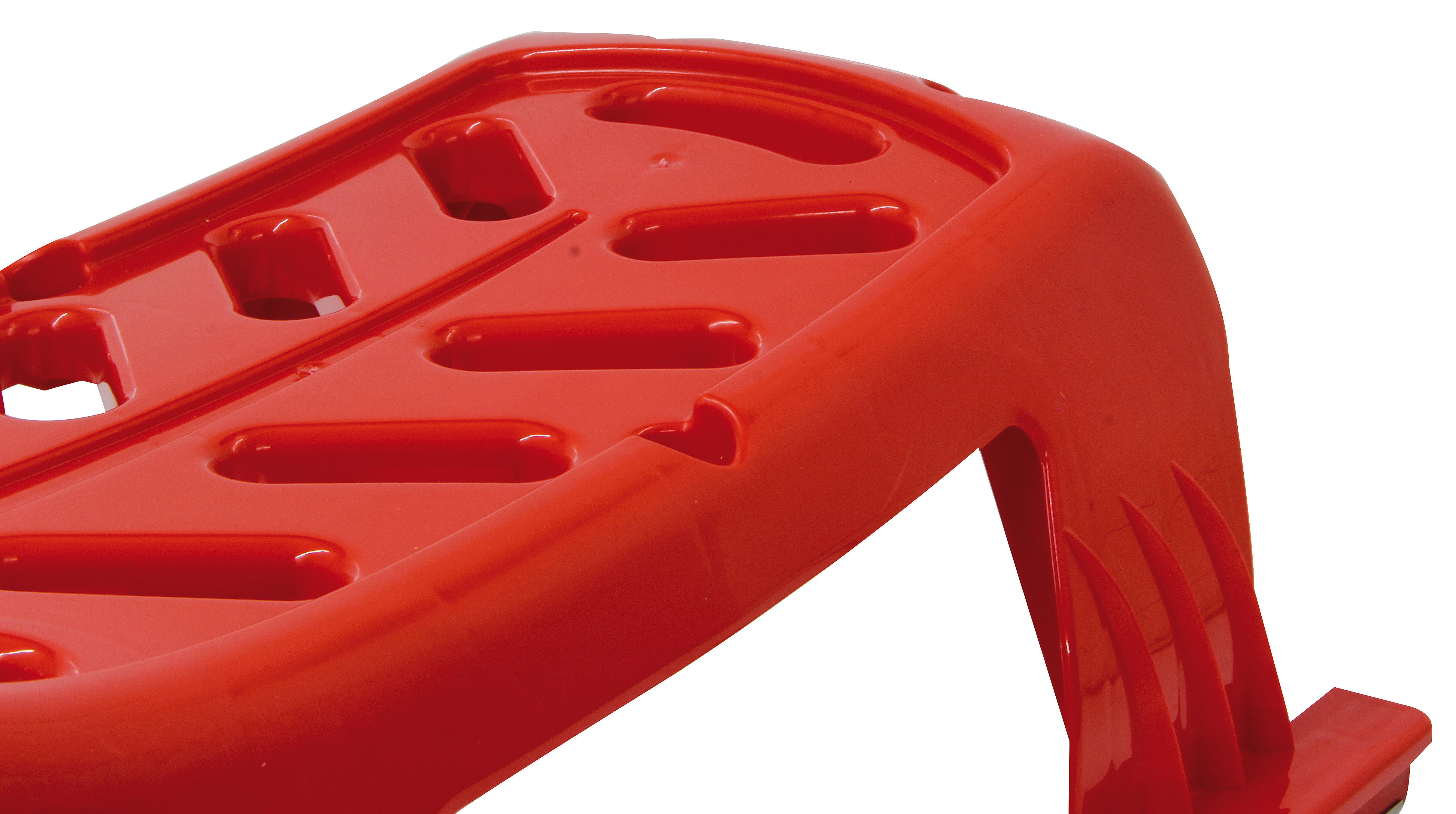Ein rotes Plastikobjekt mit Aussparungen und gerippten Kanten.